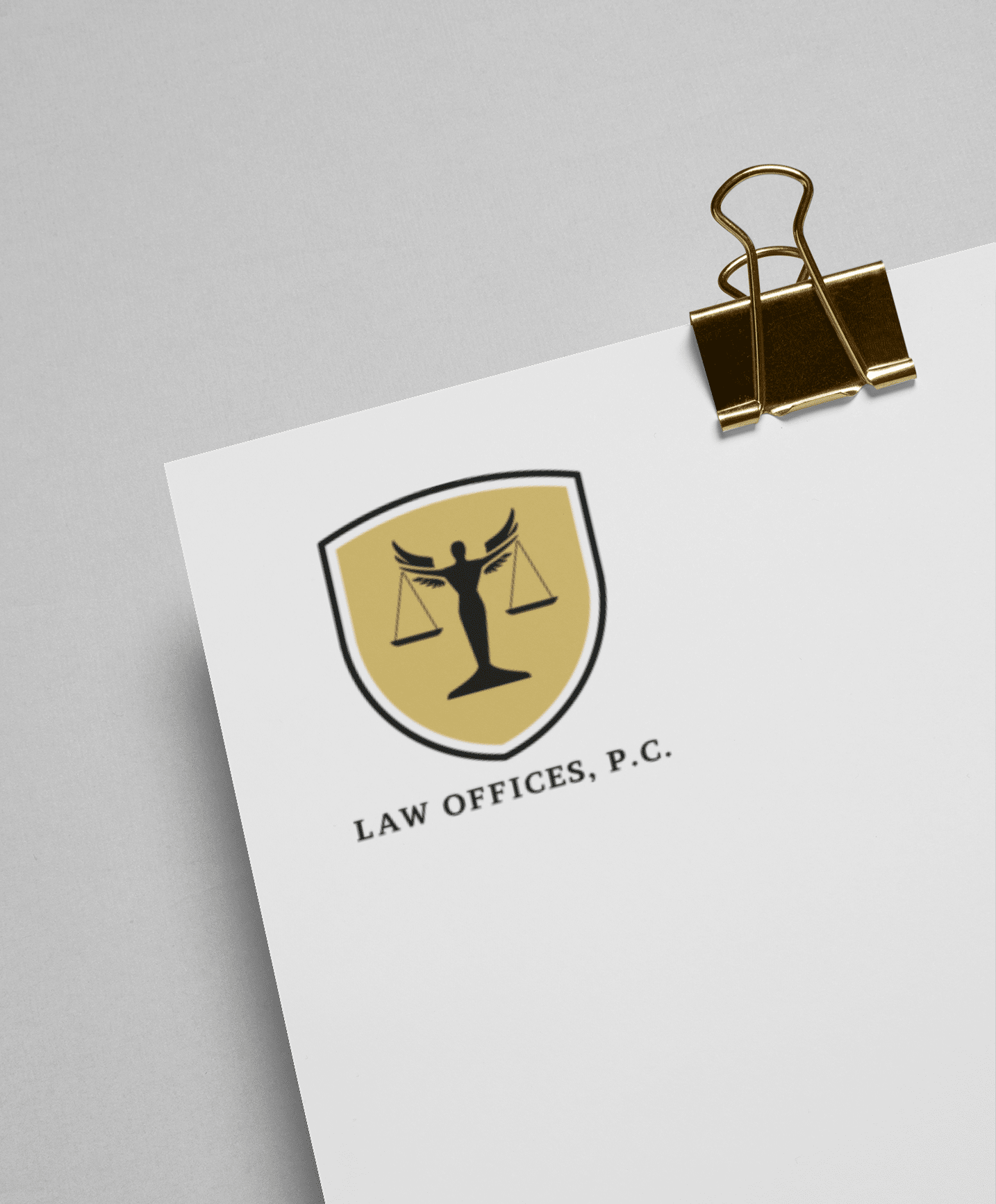 A sheet of paper clipped with a gold binder features a law office logo design of Lady Justice holding scales inside a gold shield, above the text LAW OFFICES, P.C.