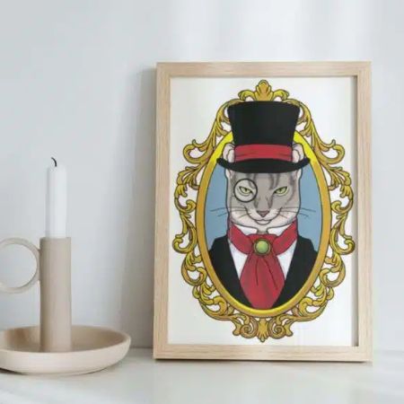 Framed artwork of a cat dressed in a suit, red cravat, and top hat, illustrated within an ornate gold oval frame—a charming piece that adds character to any branding or creative support workspace. Frame rests on a white surface beside a beige candle.