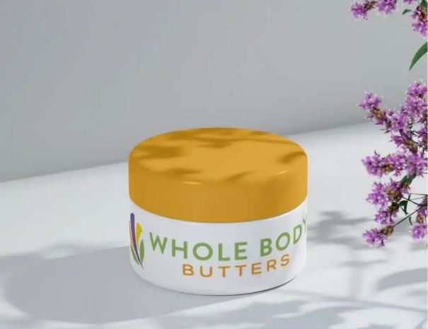 A white jar with a yellow lid labeled WHOLE BODY BUTTERS sits on a light surface, its logo design clearly visible. Purple flowers adorn the right side, while plant shadows create an inviting backdrop.
