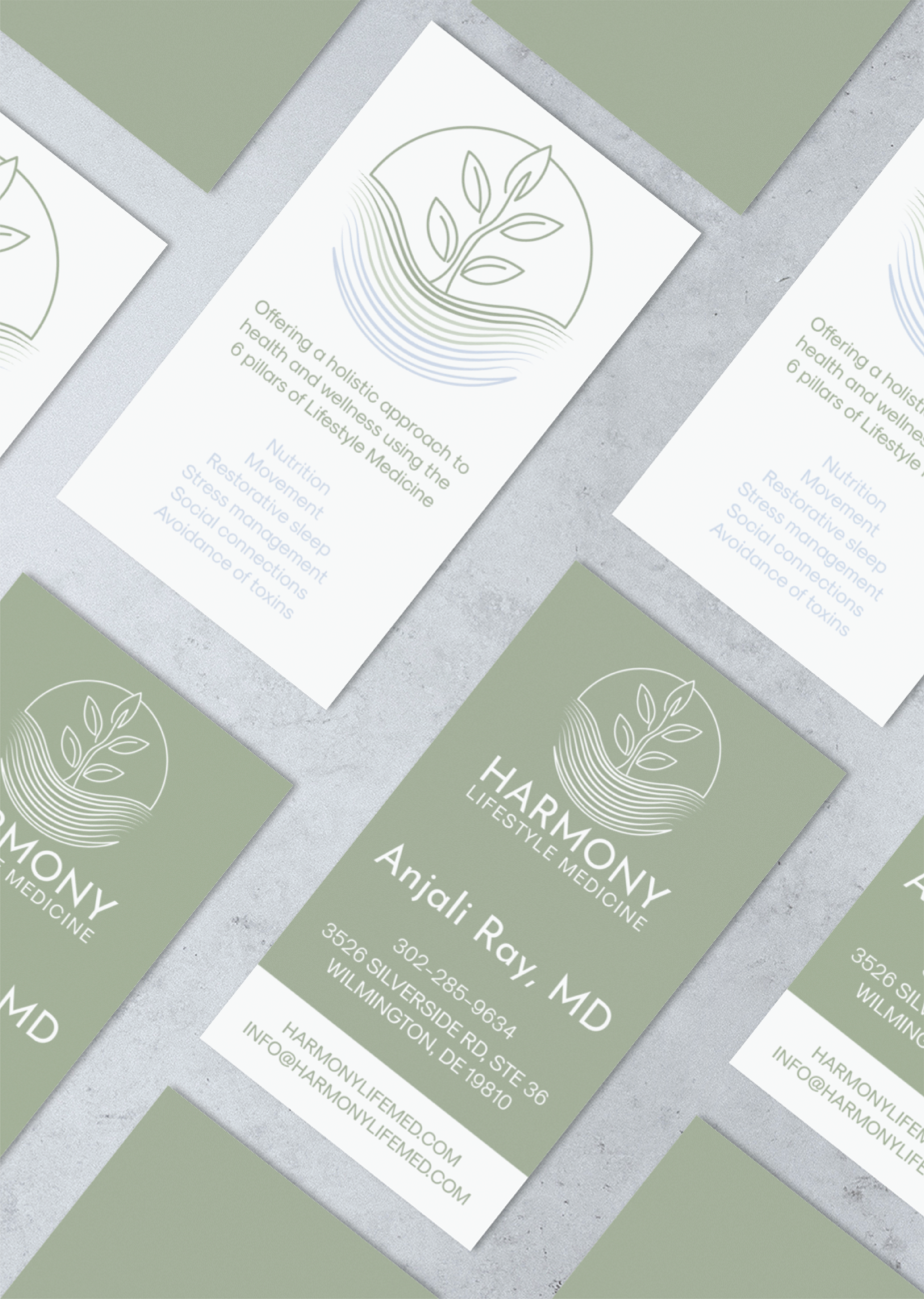 Business cards for “Harmony Lifestyle Medicine” arranged on a gray surface. The green and white branding features a leaf logo and contact details for Anjali Ray, MD—perfect for lifestyle coaches looking to connect or enhance their website design.
