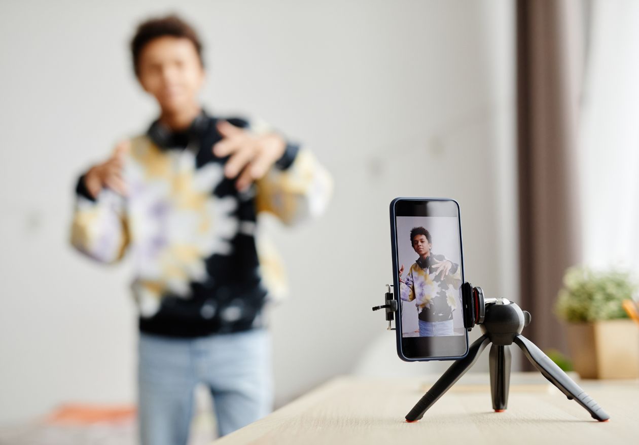 A man holds a phone in front of a tripod, illustrating effective content repurposing strategies for enhanced engagement. 