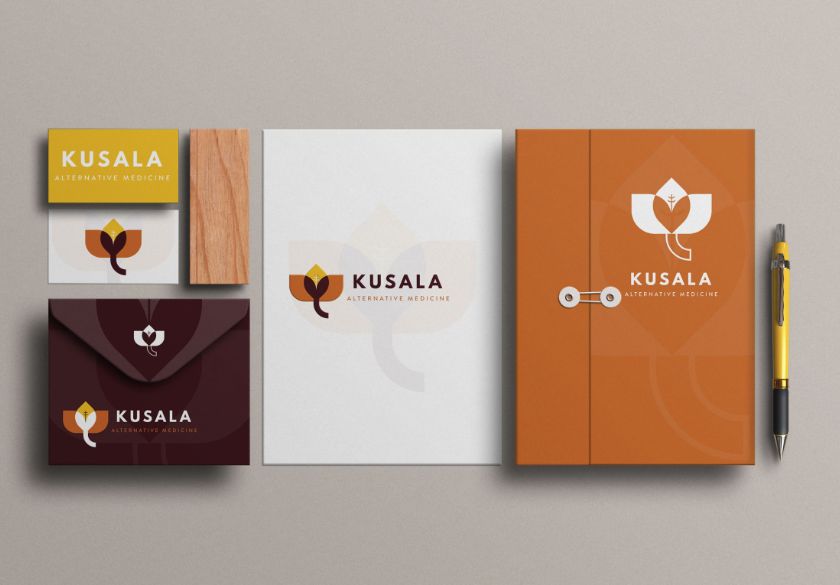 A branded stationery set for Kusala Alternative Medicine, featuring a custom logo design—a stylized flower in brown, orange, yellow, and white—across business cards, envelopes, folders, notepads, and a pen.