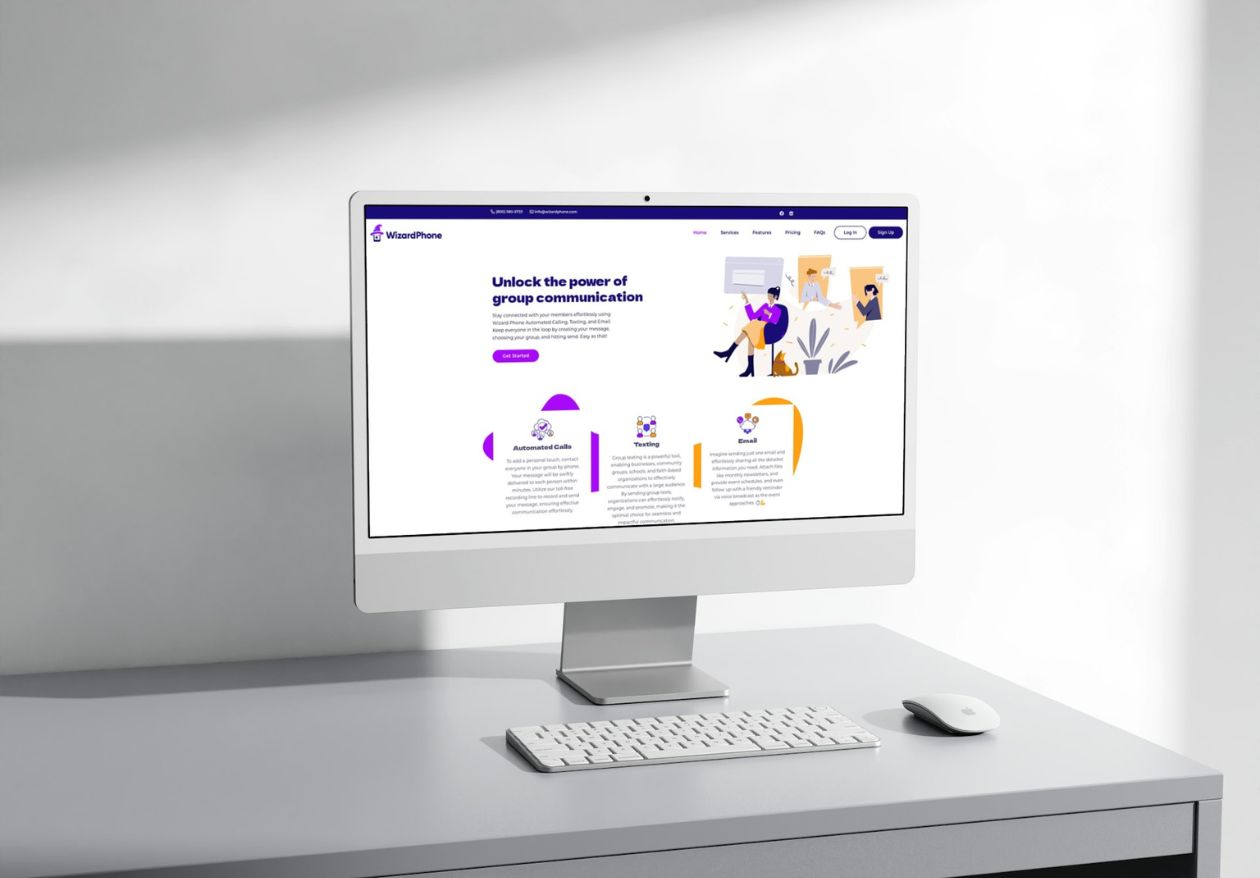 A desktop computer on a gray desk displays a website with the header Unlock the power of group communication, illustrated graphics, and custom logo design. A keyboard and mouse sit nearby as sunlight casts shadows on the white wall.