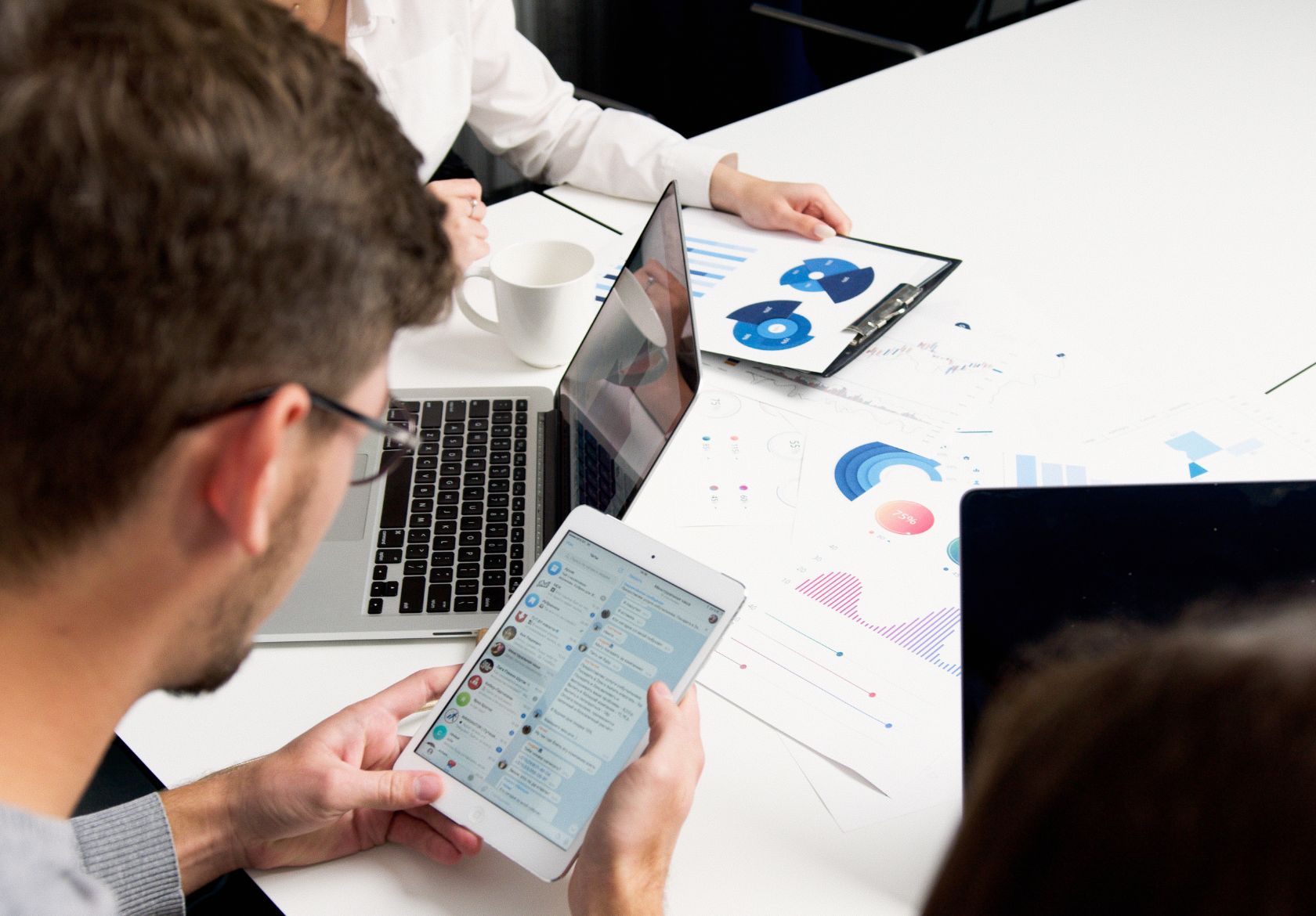 A diverse group collaborates around a table, engaging with a laptop to strategize content and assess platform suitability.
