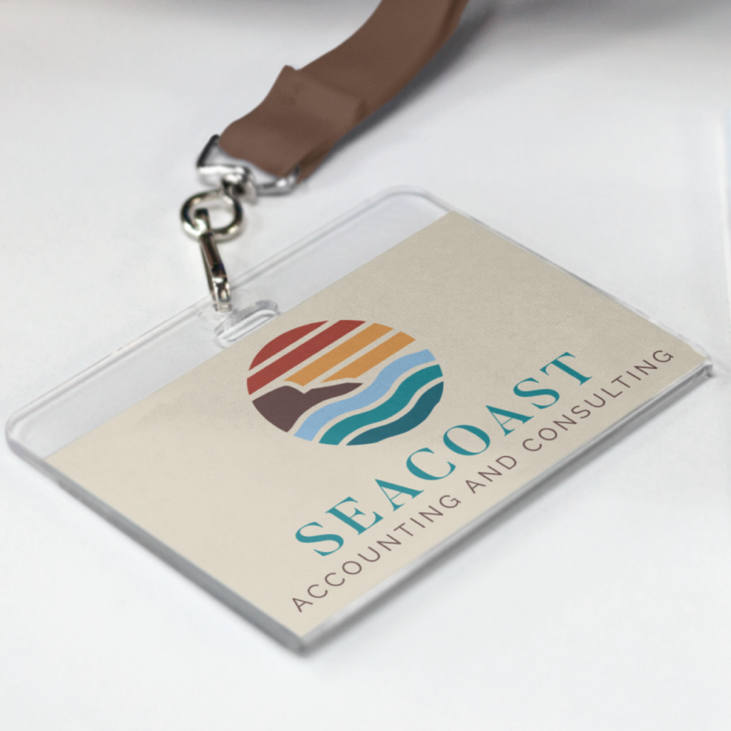 A name badge with a brown lanyard displays the SEACOAST Accounting and Consulting logo—featuring a stylized sun, waves, and coastline—showcasing strong branding in warm colors on a light background.