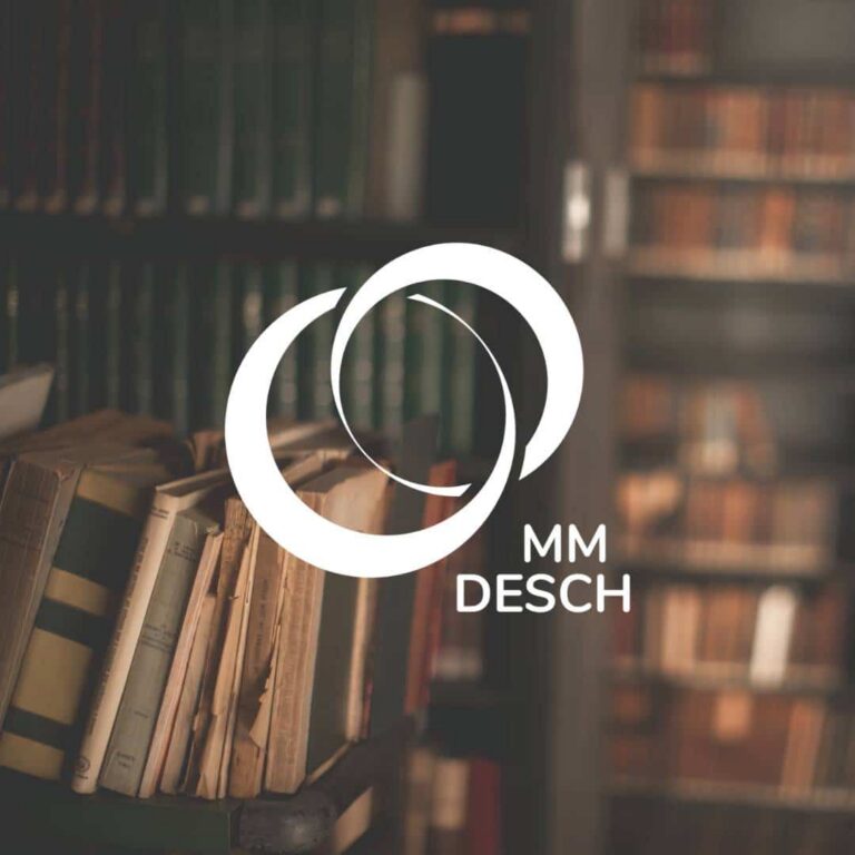 A blurred bookshelf filled with books in the background. In the foreground, a white custom logo design of two overlapping circles and the text MM DESCH appear prominently.