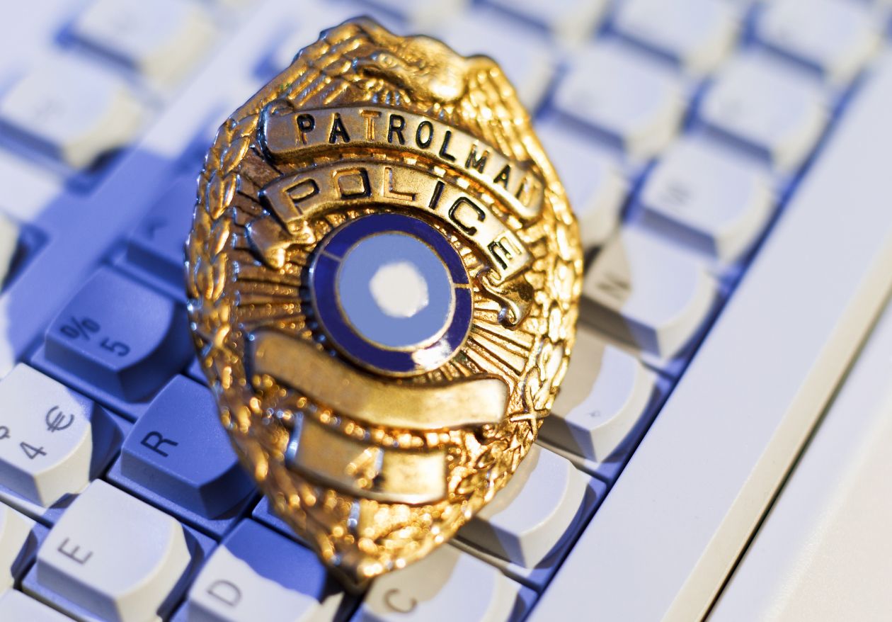A gold police patrol badge rests on a white computer keyboard, symbolizing the intersection of law enforcement and technology—a fitting image for Moonlit Media, where web design services blend security with innovation.