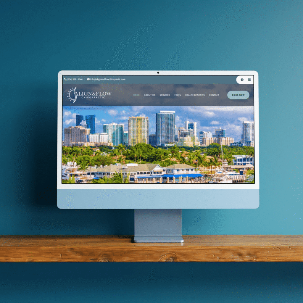 A desktop computer on a wooden shelf displays a website with a city skyline, palm trees, and waterfront buildings against a blue sky, set against a teal wall background—showcasing Moonlit Medias web design services.