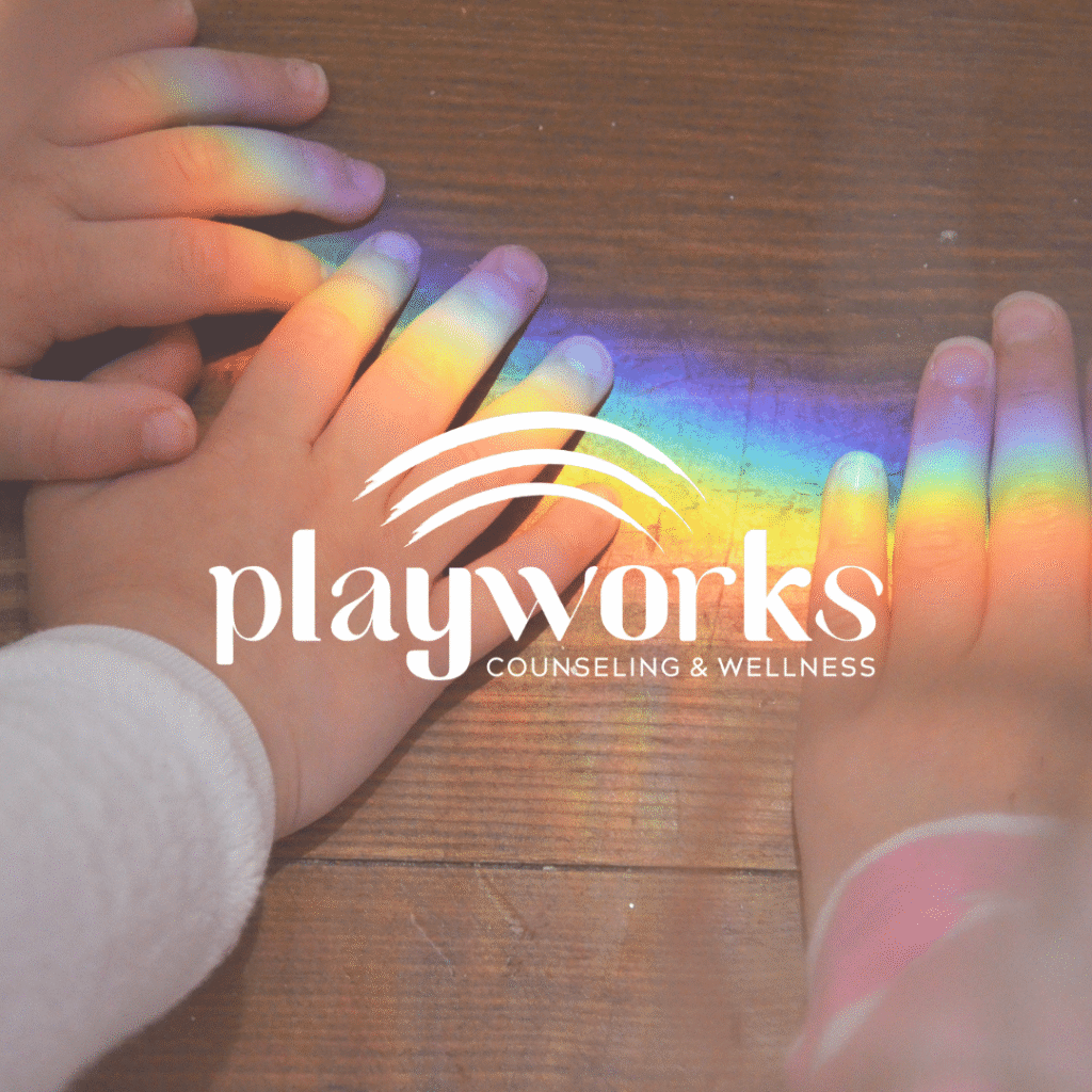 Two childrens hands touch a beam of rainbow light on a wooden surface. The Playworks Counseling & Wellness logo, created through custom logo design, is displayed over the image.