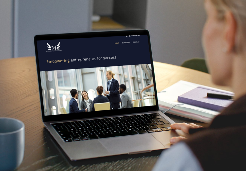 A person using a laptop at a desk views a website showing a group of professionals in a business meeting, with the text Empowering entrepreneurs for success and tips on how to brief a designer for the best design results.