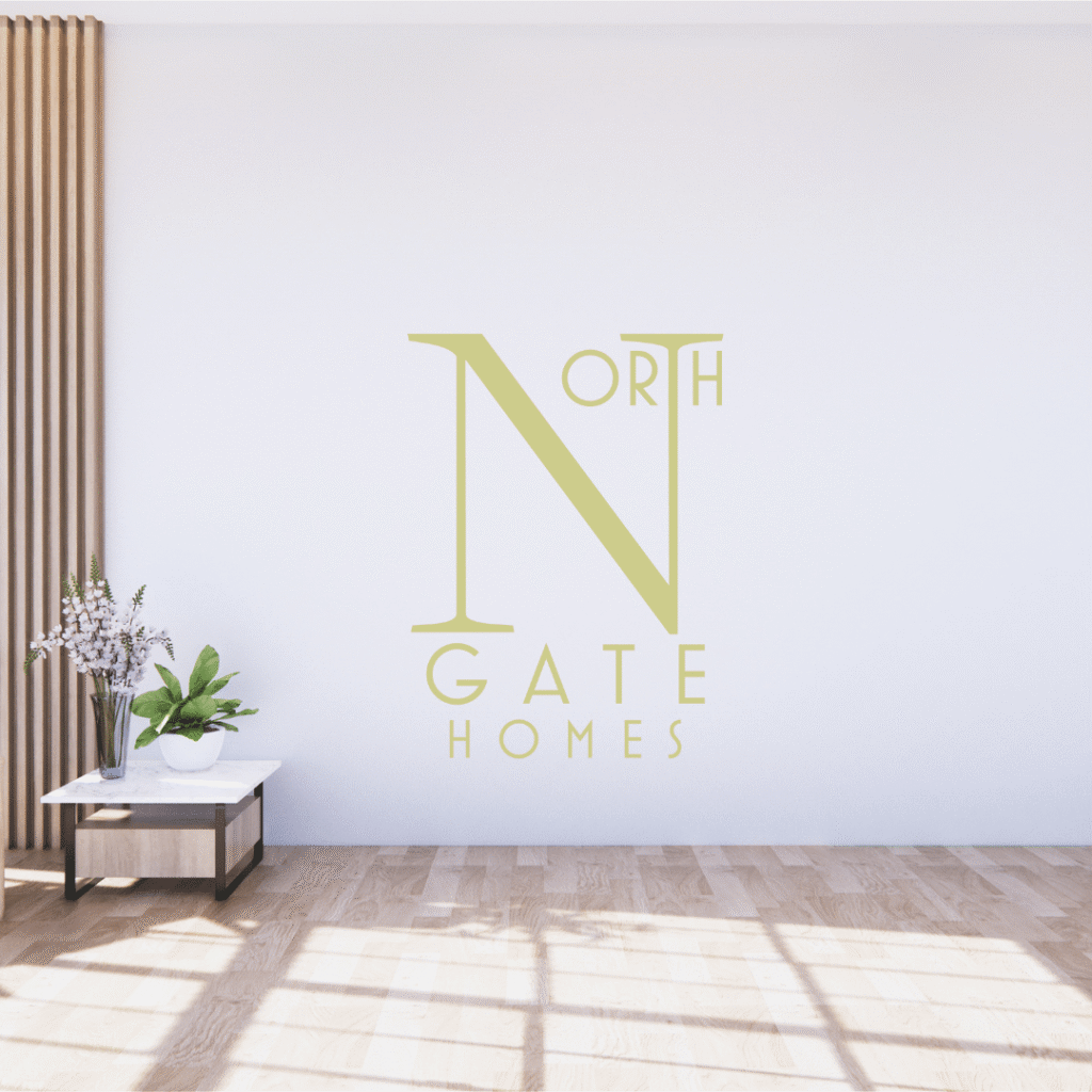 A minimal, sunlit living space with light wood floors, a small white table with a plant and flowers, and a large North Gate Homes logo—showcasing elegant logo design services—on a pristine white wall.