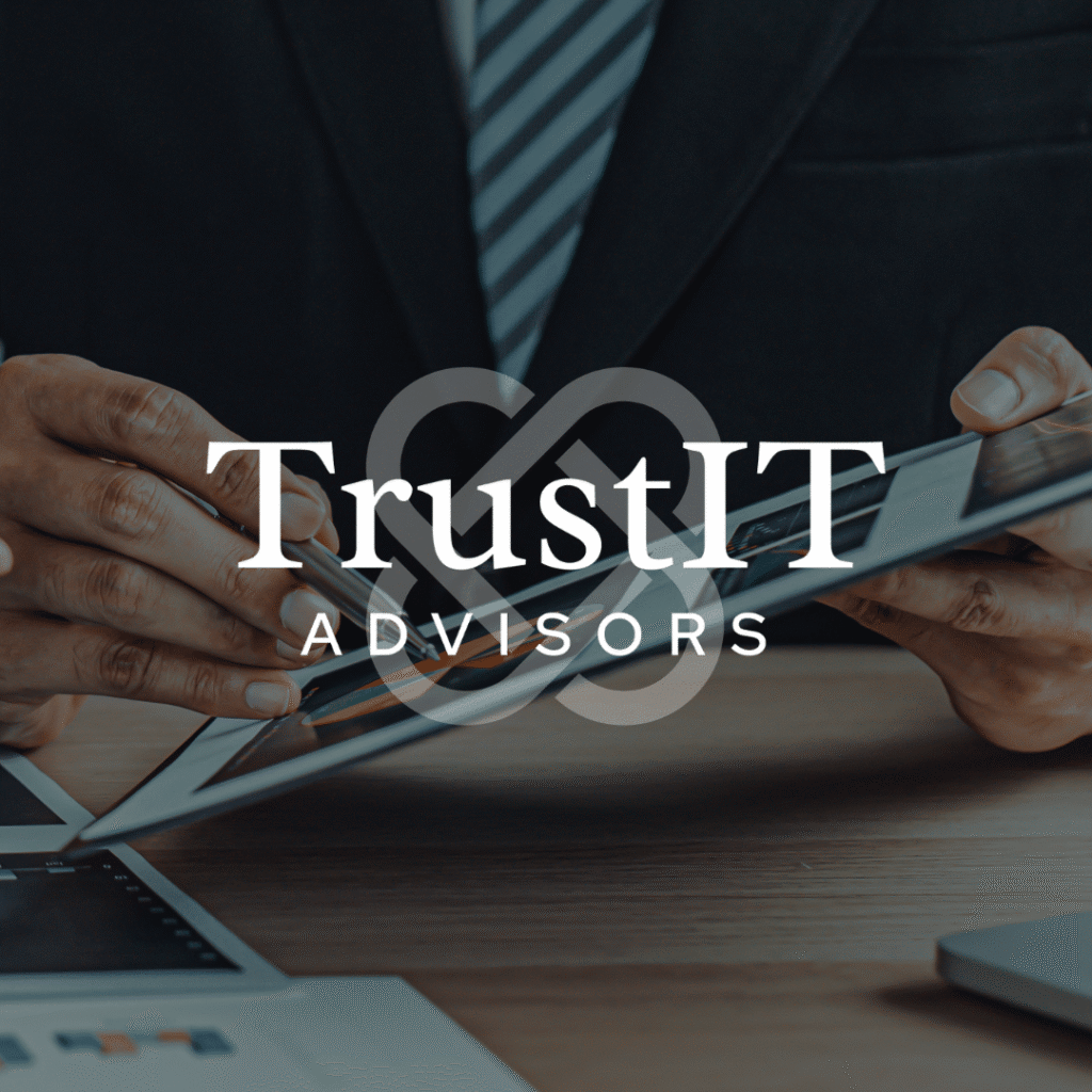 A person in a suit uses a tablet at a desk with documents, overlaid with the TrustIT Advisors logo in white text, showcasing custom logo design by Moonlit Media.