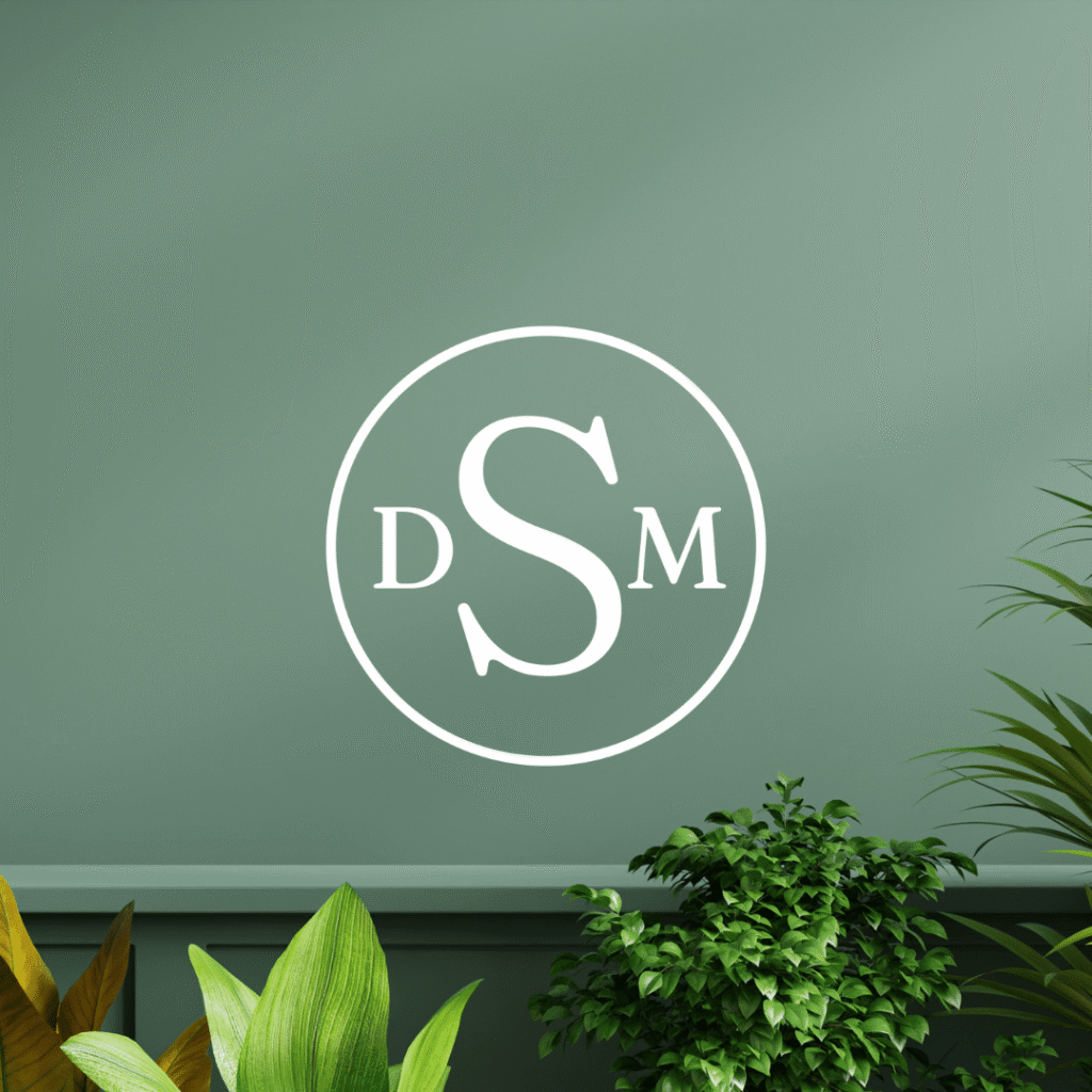 A white circle with the letters DSM inside it is displayed on a green wall, surrounded by leafy green plants at the bottom—a showcase of Moonlit Media’s logo design services.