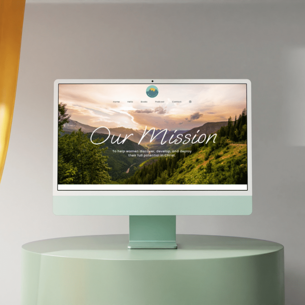 A desktop computer on a green table displays a website with a scenic mountain landscape and the words Our Mission in large script text, showcasing Moonlit Medias web design services. The site menu is visible above the image.