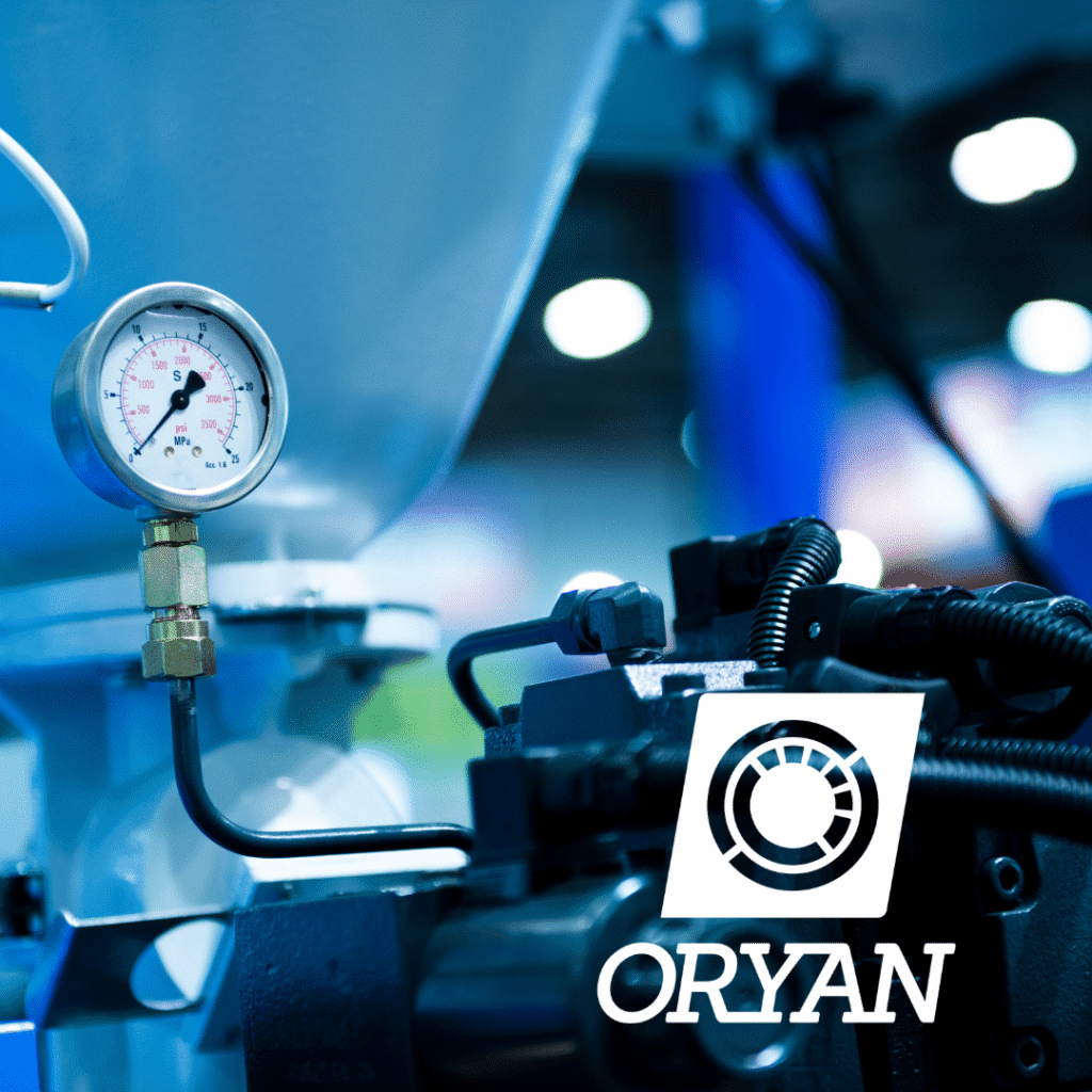 A close-up of industrial machinery with a pressure gauge and wires, featuring the ORYAN custom logo design in the foreground. The background is blurred with blue and white tones.