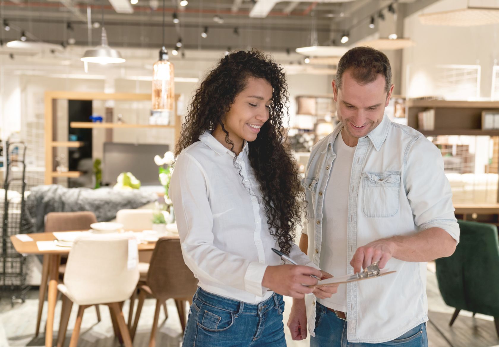 A couple stands in a furniture store, using a tablet to compare styles and make informed choices for their home decor.