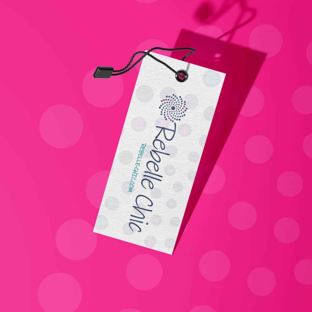 A white textured clothing tag with “Rebelle Chic” and a swirl design, created by Moonlit Media’s custom logo design service, hangs by a black string, casting a shadow on a bright pink background with large light pink polka dots.