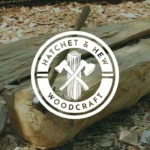 A detailed logo reading Hatchet & Hew Woodcraft features two crossed hatchets over a log. In the background, a hatchet is embedded in a large log among wood shavings outdoors, highlighting the logo difference from standard logos.