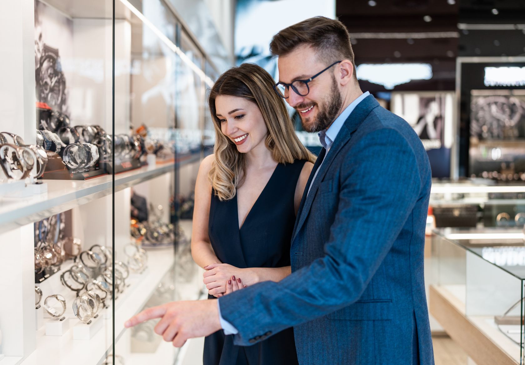 A man and woman examine watches together in a stylish store, showcasing their interest in timepieces and fashion.