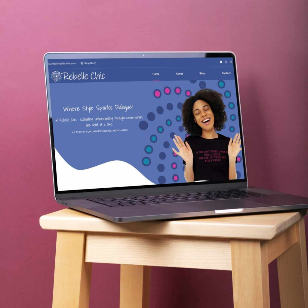 A laptop on a wooden stool displays the Rebelle Chic website, featuring a woman smiling with raised hands against a blue background with colorful dots. Showcasing custom website design, the text reads, Where Style Sparks Dialogue!.