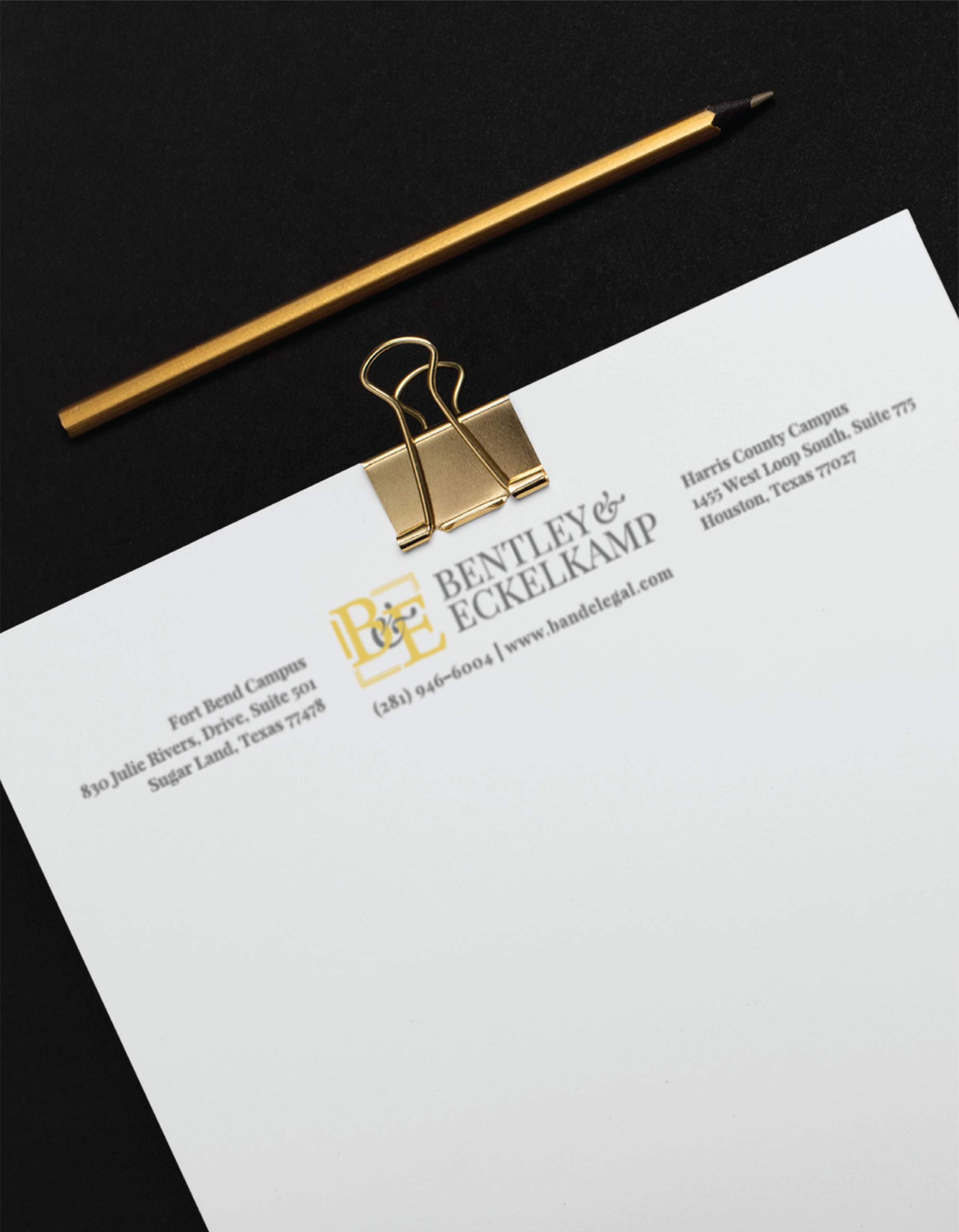 | Moonlit Media LLC A gold pencil and binder clip rest on a letterhead for Bentley & Eckelkamp, showcasing sophisticated branding with addresses and contact details in black and gold text on white paper, against a black background.
