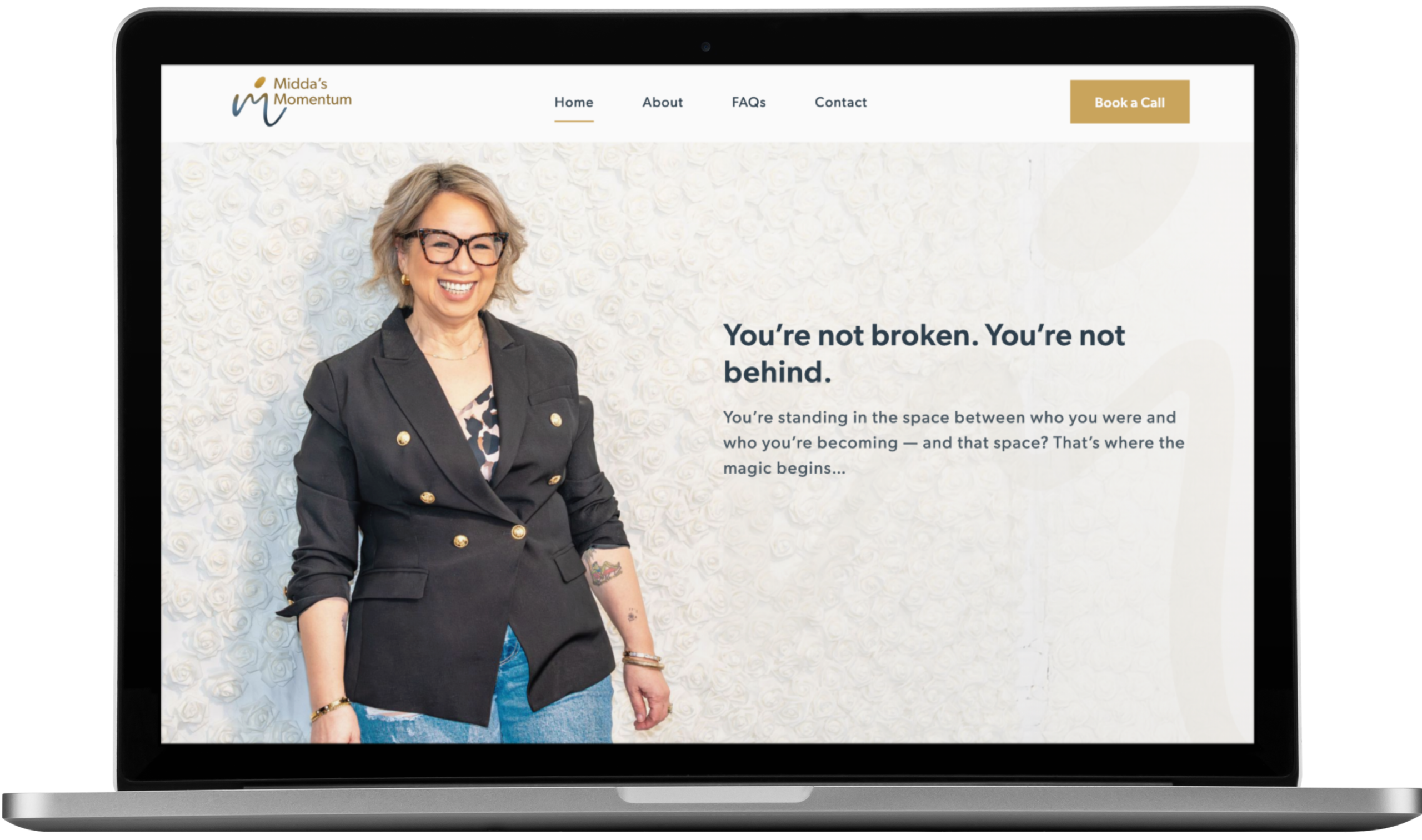 A minimalistic desk setup with a computer displaying a website design, a smartphone on a stand, a notepad, pen, and glasses. The desk sits by a window with light curtains and autumn trees visible outside—perfect for creative support.