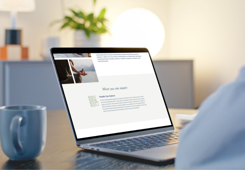 A person sits at a desk with a laptop displaying a webpage titled What you can expect. Perfect for finding website bio tips, the scene features a mug on the desk and blurred plant and lamp in the background.