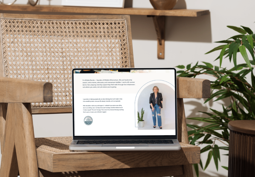 A laptop sits on a wooden chair, displaying a website with a photo of a woman standing near a white arch. Text and a logo are visible on the left side, possibly offering website bio tips. A plant and shelf are in the background.