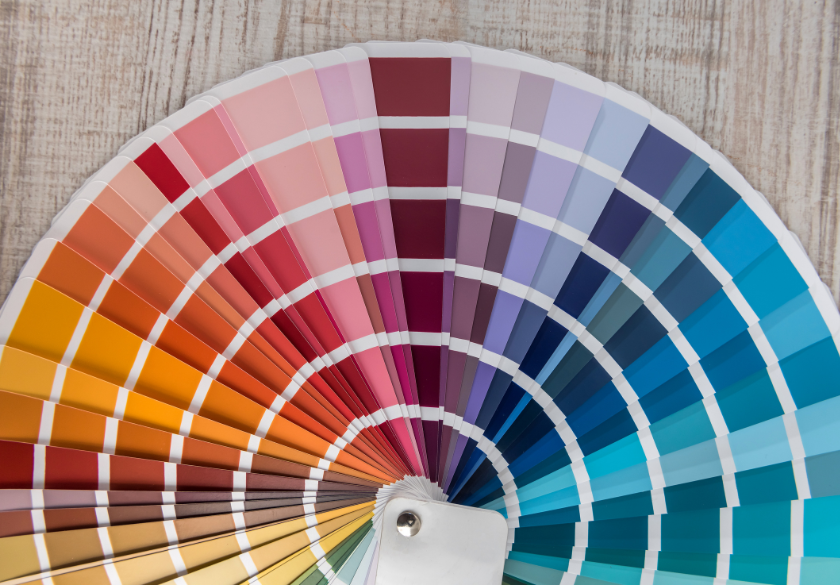 How to Choose the Right Color Palette for Your Brand color psychology A fan-shaped color palette with various paint swatches arranged in a gradient, perfect to help you choose shades that reflect your brand personality, displayed on a light wooden surface.