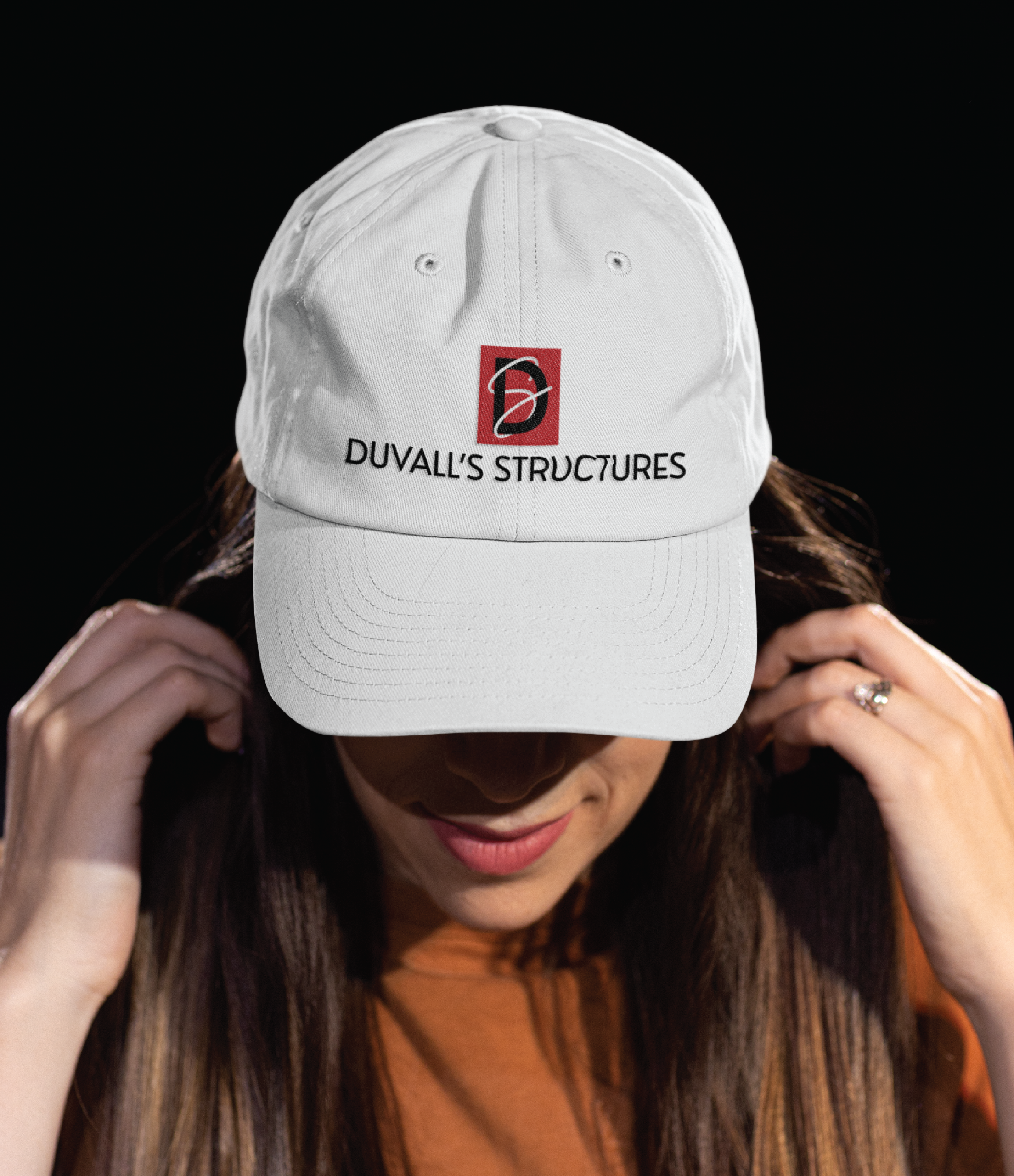 Woman wearing a white baseball cap with a red and black logo and the text DUVALLS STRUCTURES embroidered on the front, against a dark background—perfect for showcasing your custom website design in Philadelphia PA.