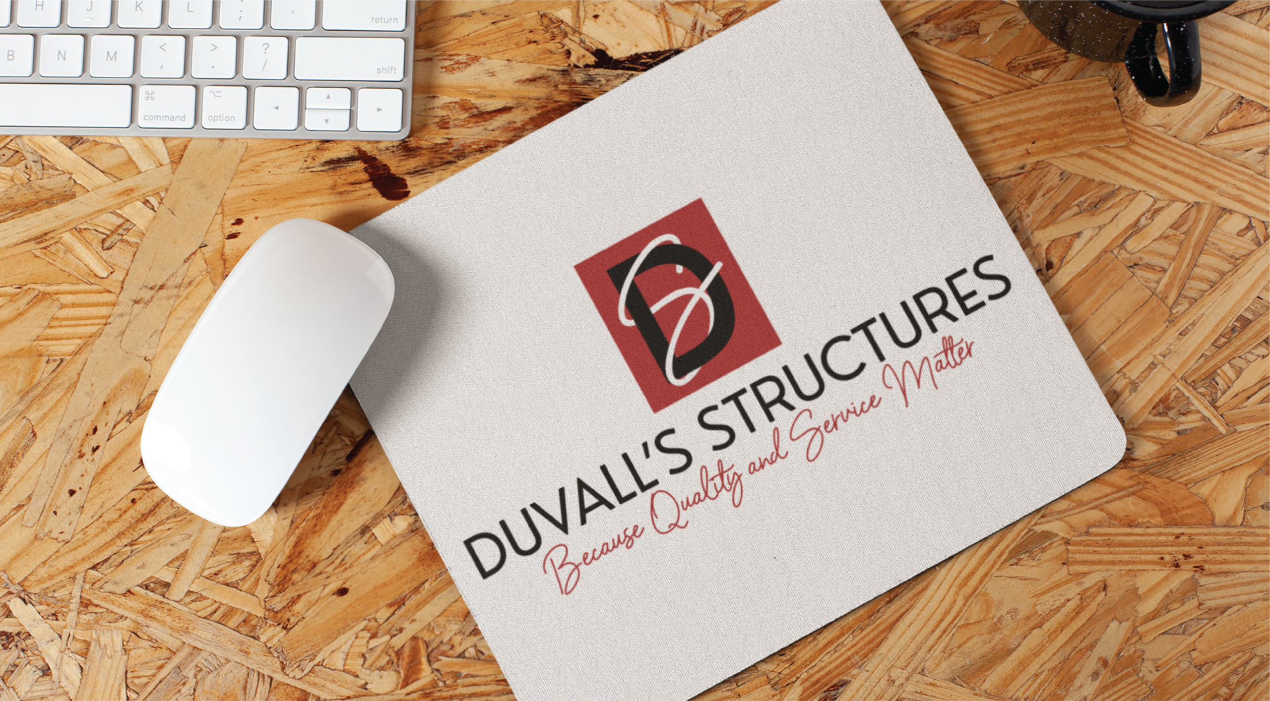 A white mouse and keyboard on a wooden desk next to a mouse pad printed with the DUVALLS STRUCTURES logo and the tagline Because Quality and Service Matter, perfect for any Philadelphia office or custom website design workspace.