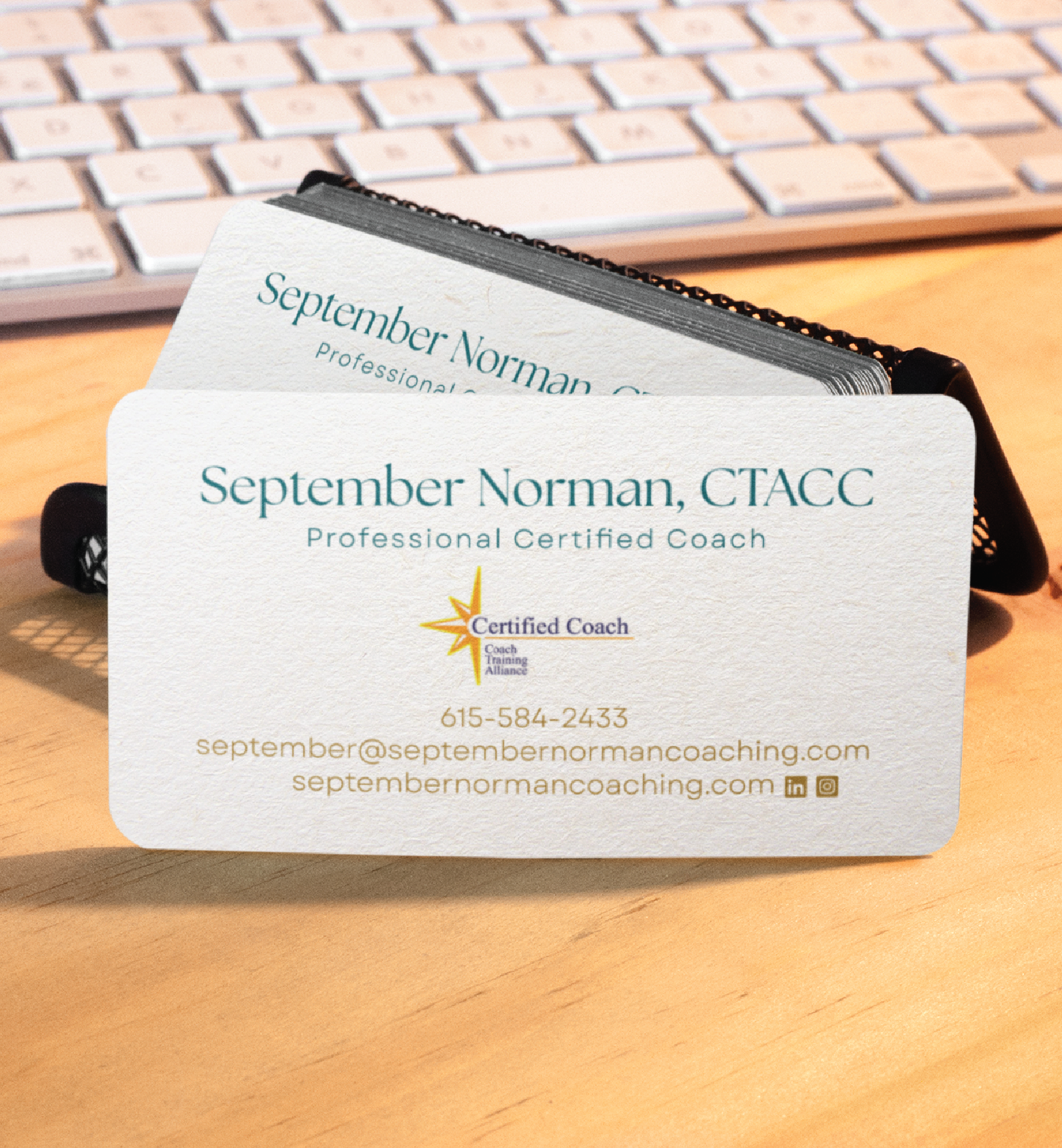 A custom business card for September Norman, CTACC, Professional Certified Life Coach in Tennessee, displays contact details, certification logo, email, website, phone number, and social media icons beside a computer keyboard.