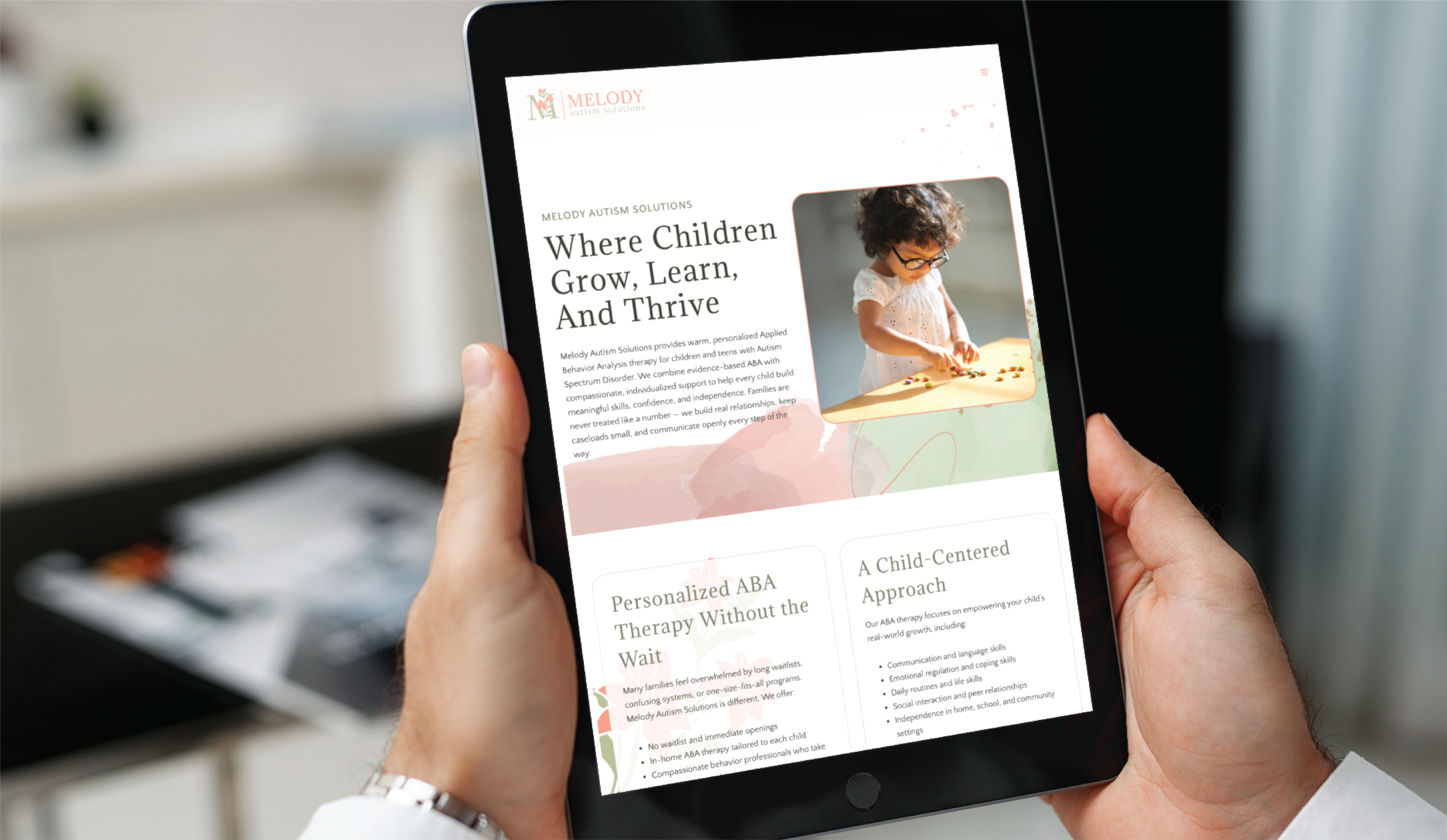 A person holds a tablet displaying a custom website design for Melody Autism Solutions, featuring the headline Where Children Grow, Learn, And Thrive and a photo of a young child playing with wooden toys.