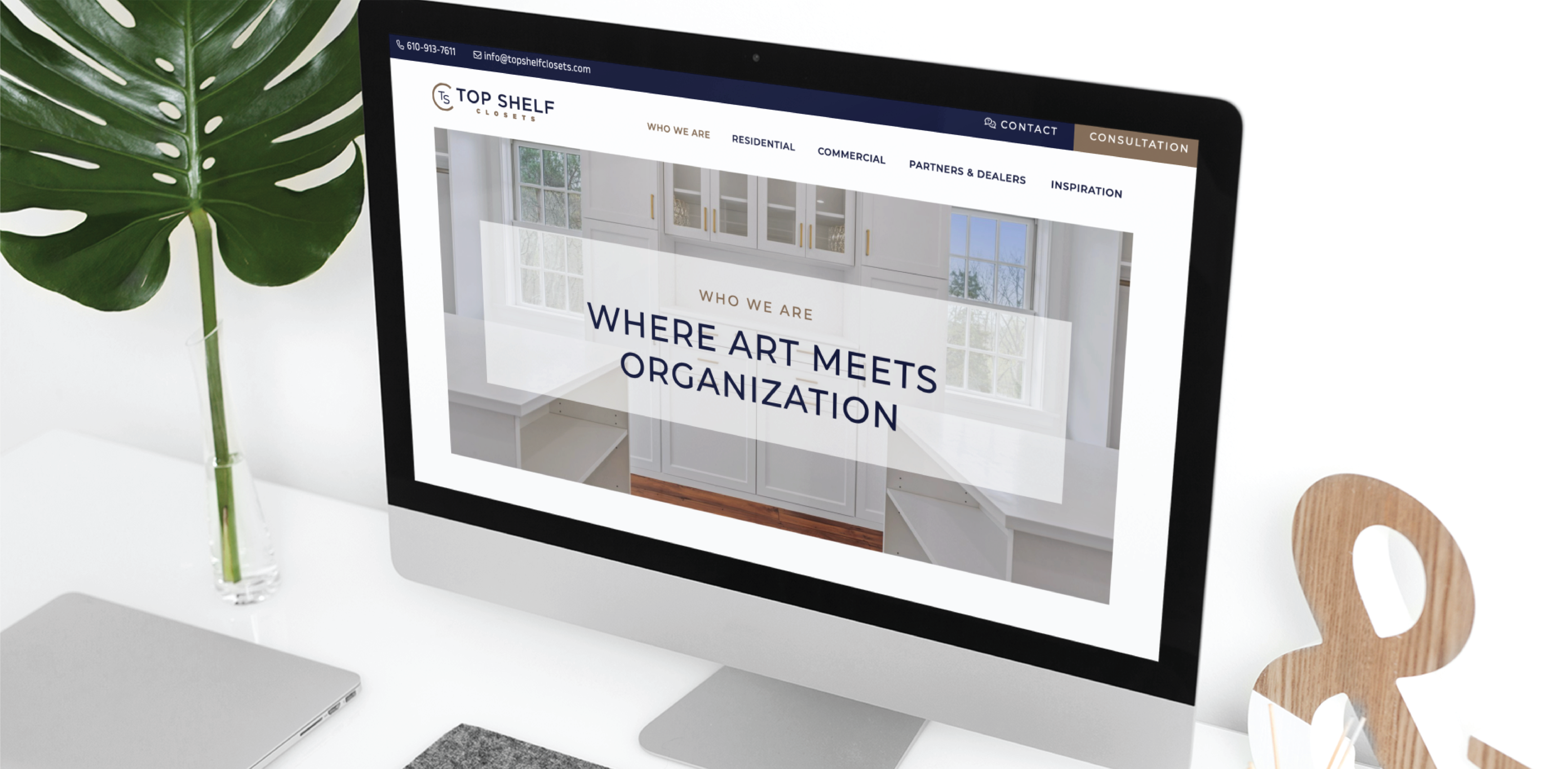 A computer monitor on a white desk displays a Web Design for Top Shelf Cabinetry with the headline WHERE ART MEETS ORGANIZATION. Office supplies and a plant are visible nearby, creating an organized workspace in South Carolina.