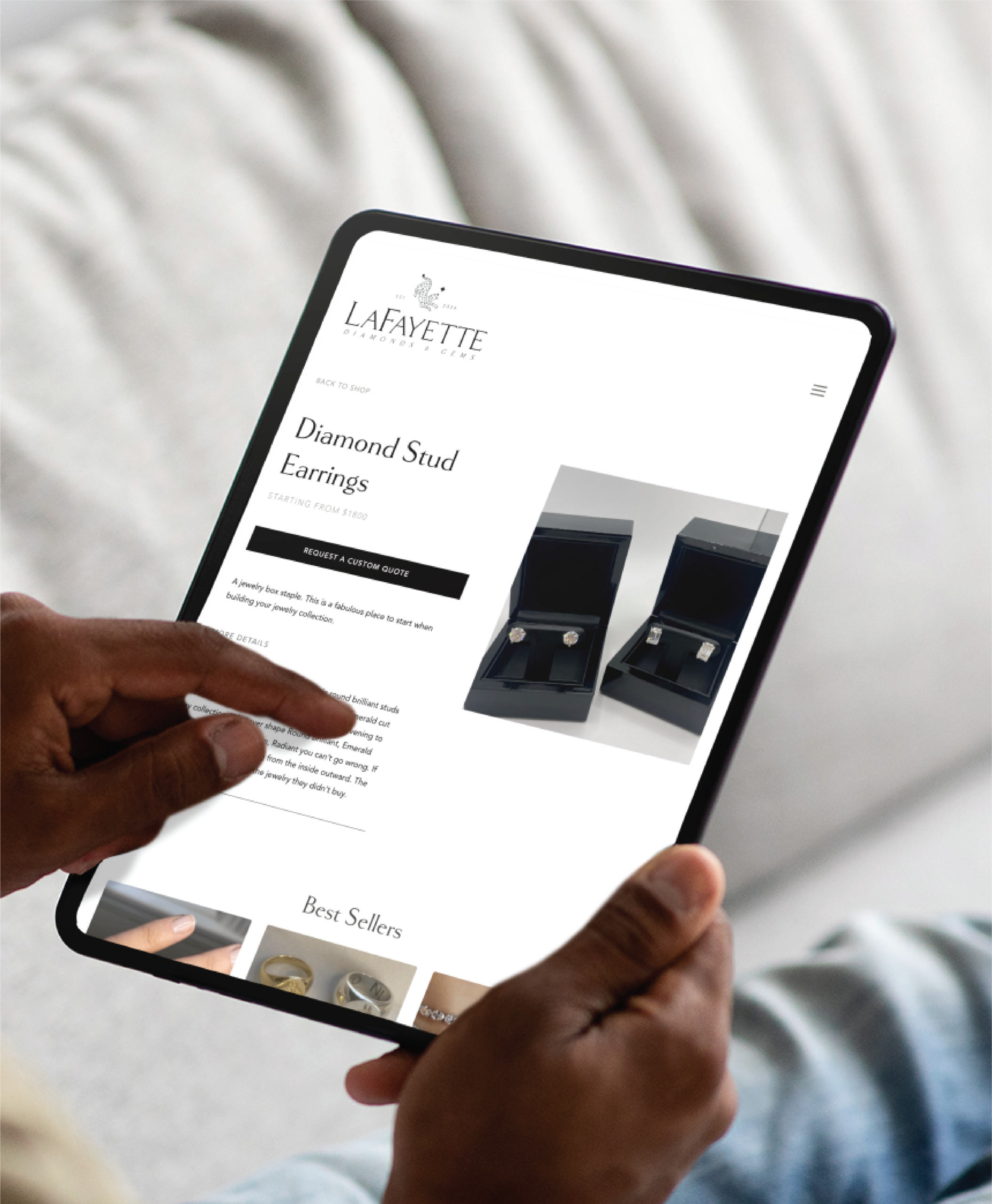 A person holds a tablet displaying a jewelry website page for “Diamond Stud Earrings” with images of two open earring boxes and sleek custom website design inspired by New York style, plus text describing the product.