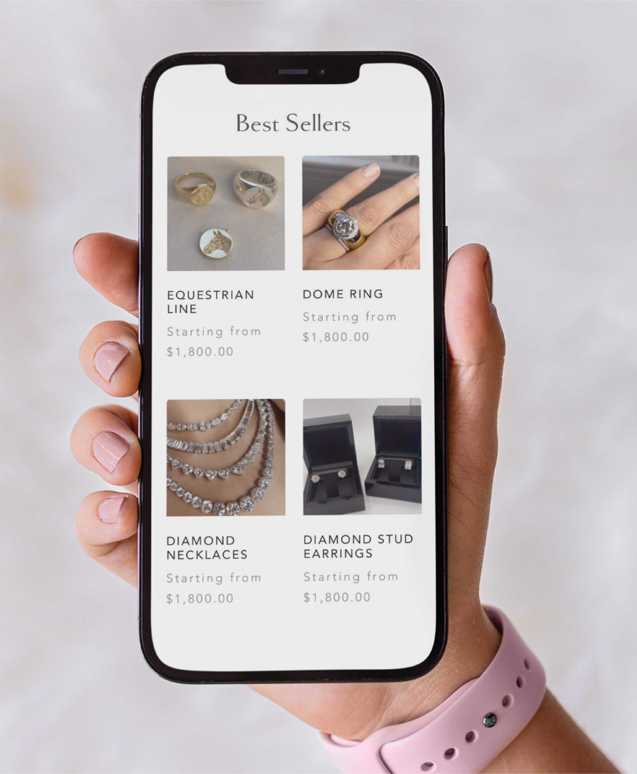 A hand holding a smartphone displays a New York jewelry website’s Best Sellers page, featuring rings, diamond necklaces, and diamond stud earrings. The person wears a pink smartwatch—showcasing the impact of custom website design.