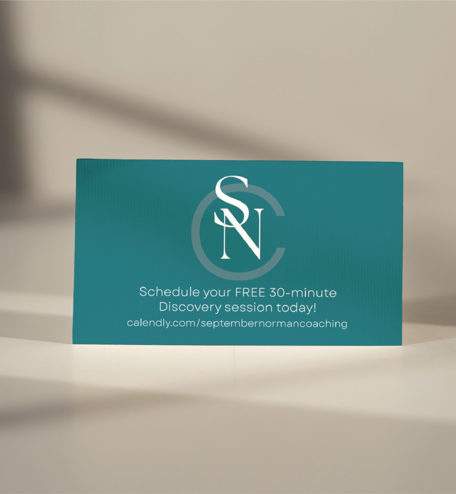 A teal business card for a Tennessee Life Coach displays a monogram SNC at the top, offering a free 30-minute discovery session and a link: calendly.com/septembernormancoaching. The card stands on a light surface.