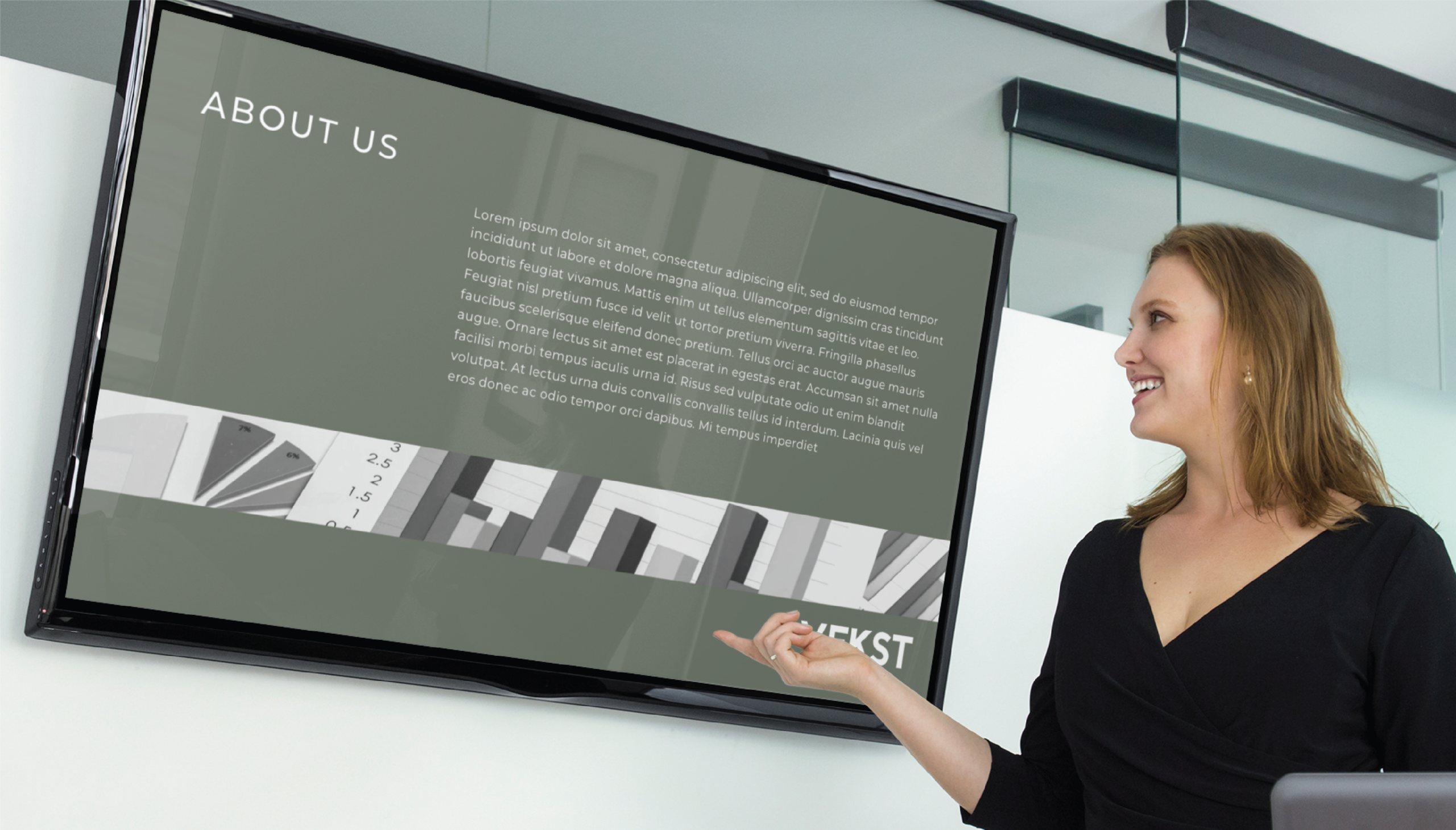 A woman in business attire stands in a modern South Carolina office, smiling and pointing at a large screen displaying an About Us slide with placeholder text, a grayscale graphic, and Web Design concepts.