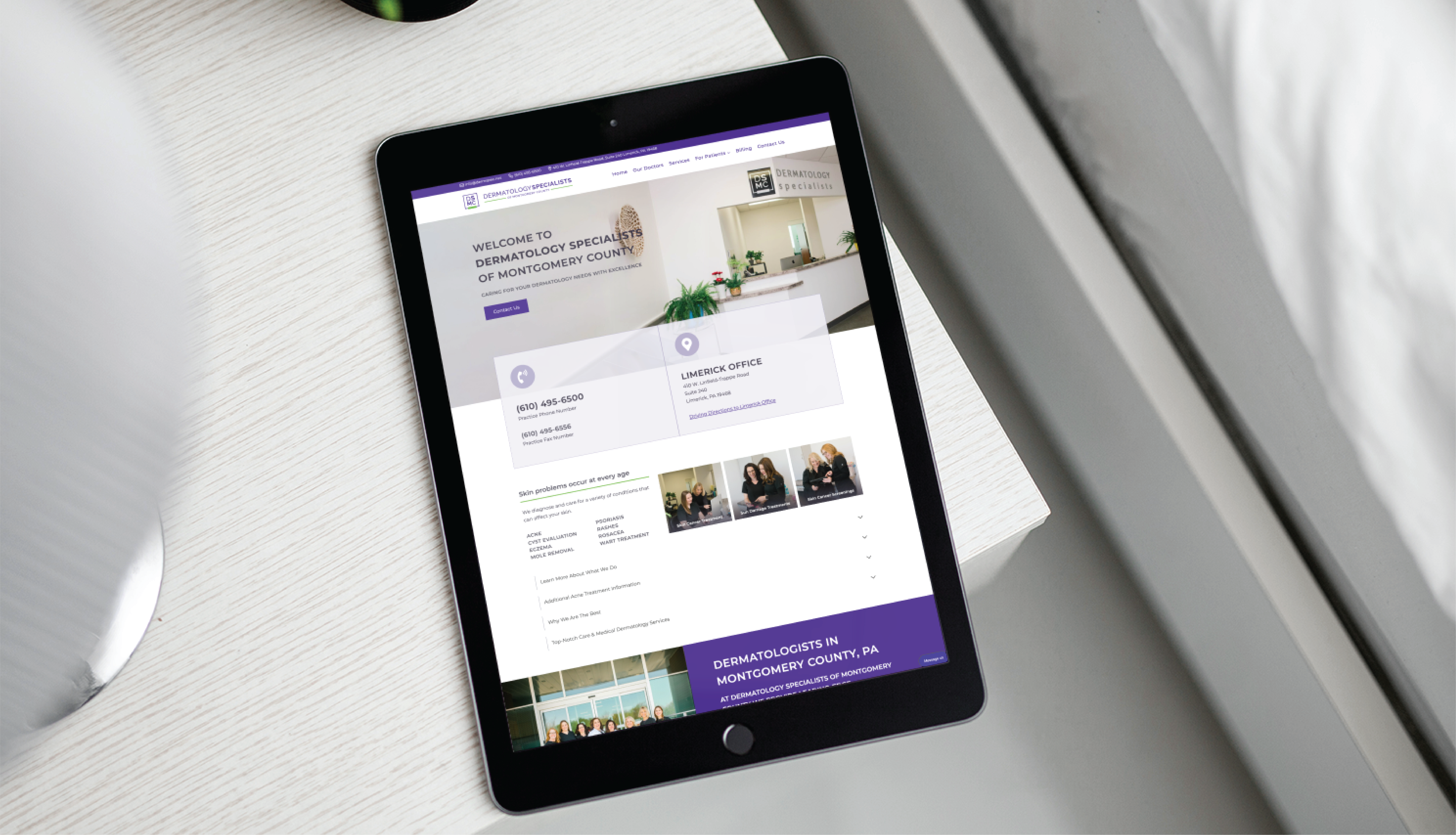 A tablet on a white table displays the homepage of Dermatology Specialists of Montgomery County, featuring modern website design elements, office information, staff photos, and a navigation menu for this Pennsylvania medical practice.