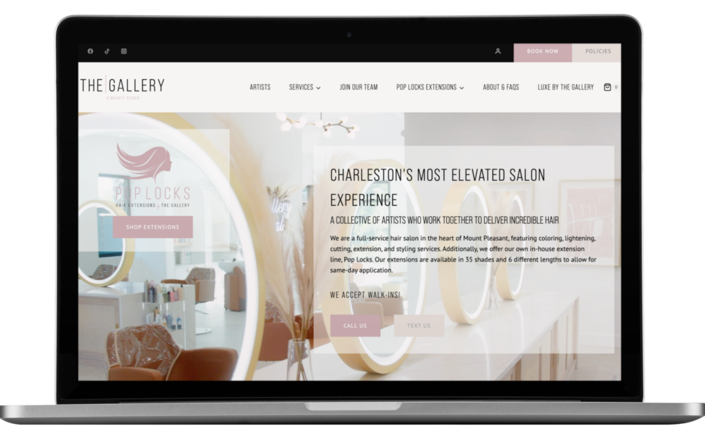 A laptop screen displays The Gallery Hair Salon’s website homepage, showcasing modern Website Design with large mirrors and round lights, plus text promoting their Charleston, South Carolina location and beauty salon services.
