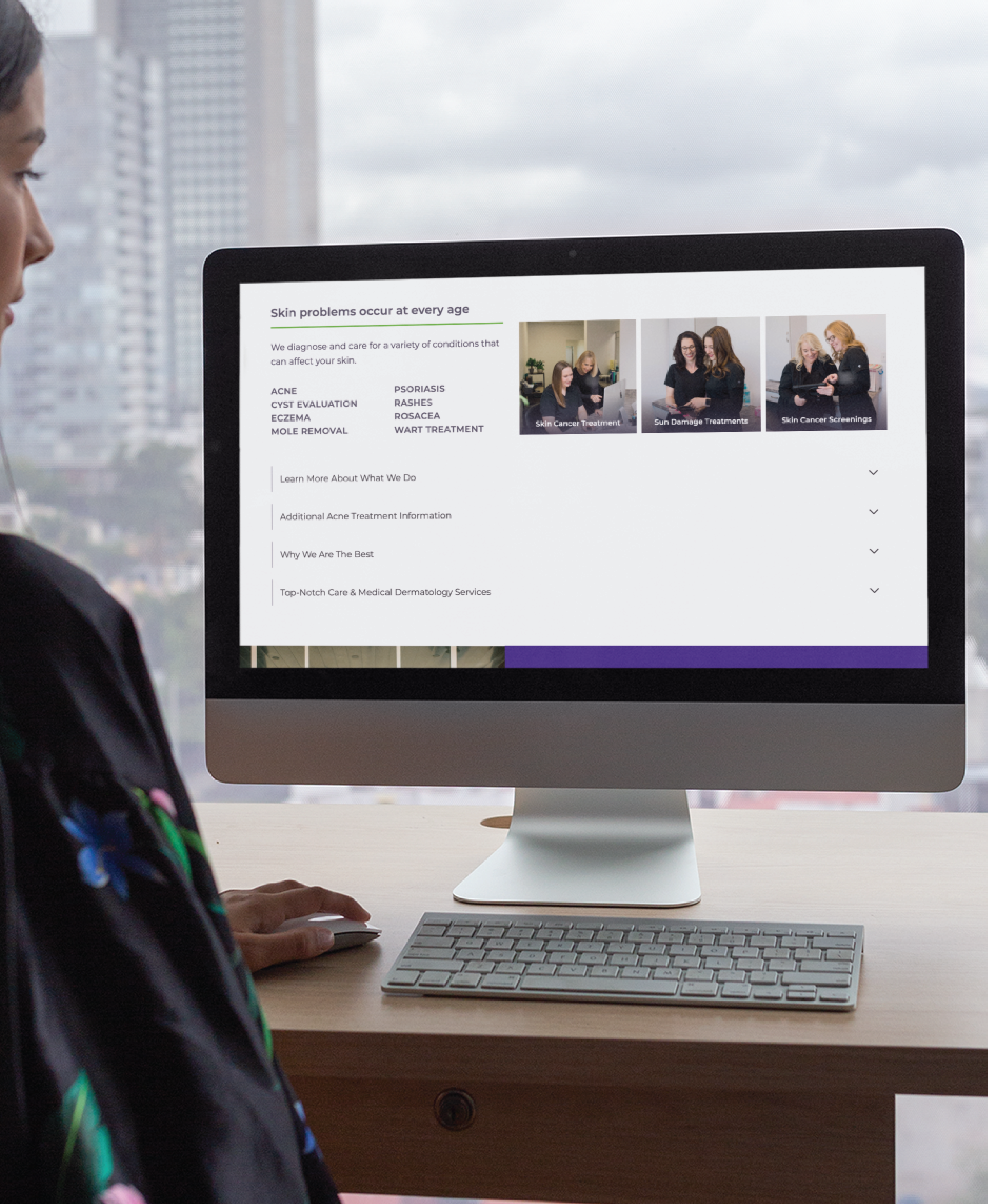 A person sits at a desk looking at a computer screen displaying a dermatology website featuring modern website design, skin treatments, and photos of dermatology professionals. A cityscape in Pennsylvania is visible through the window in the background.
