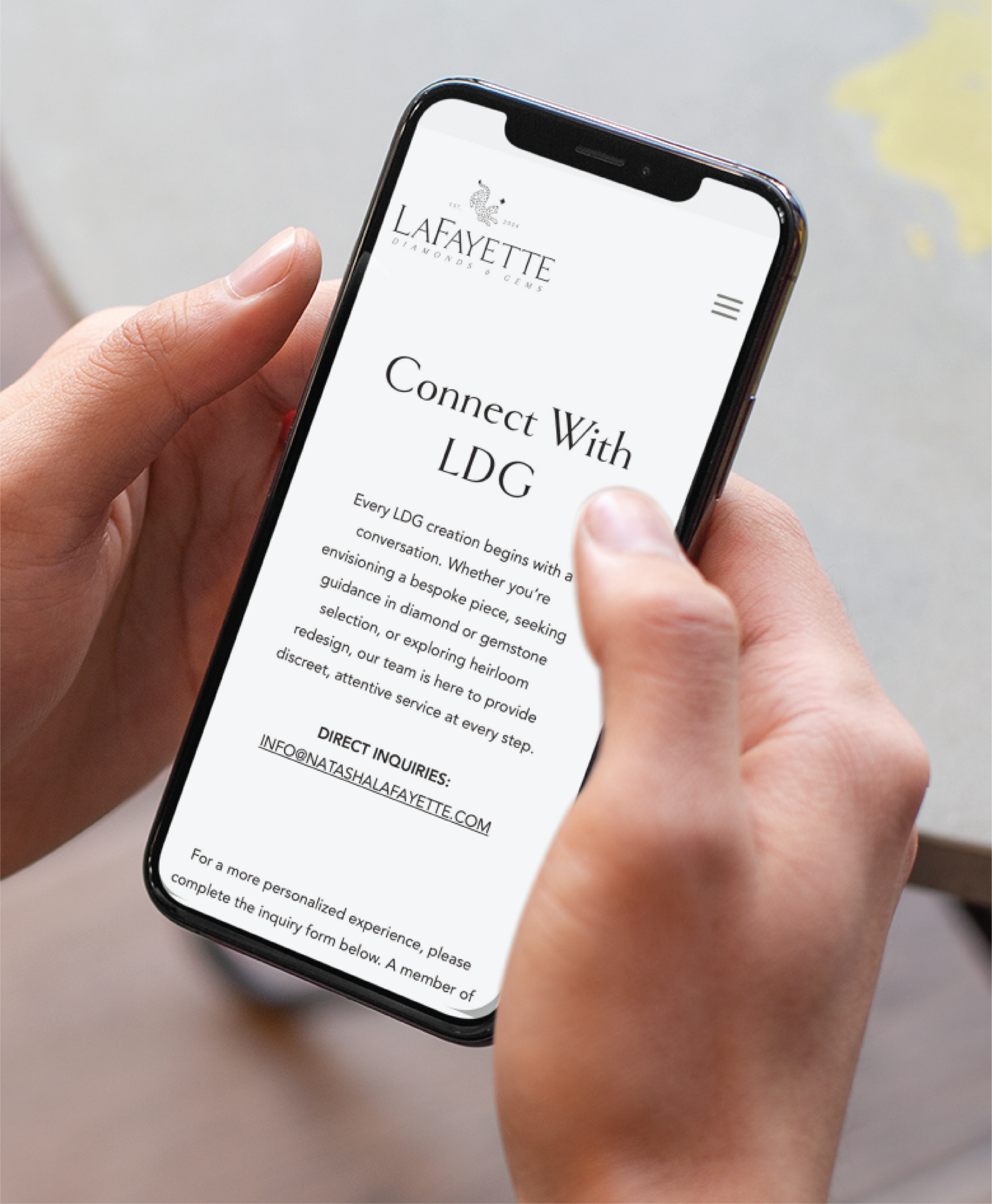 A person in New York holds a smartphone displaying the Lafayette Digital Group website, showcasing a Connect With LDG section with contact information and custom website design inquiry details on the screen.