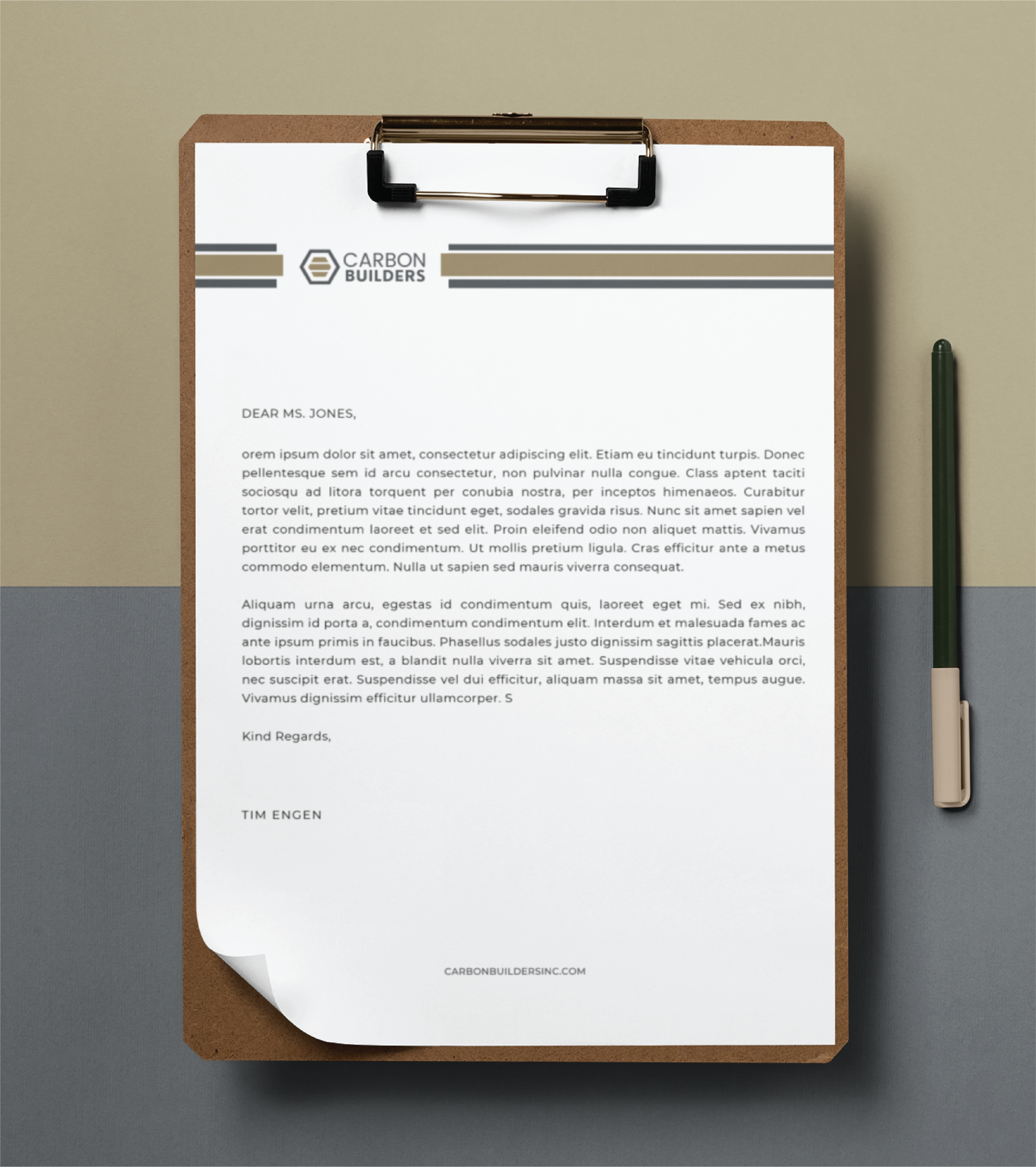 A letter on a clipboard from Michigan general contractor Carbon Builders rests on a gray surface, accompanied by a green pen. The letter is addressed to Ms. Jones, signed by Tim Engen, with the company’s logo and website featured in the stationery design.