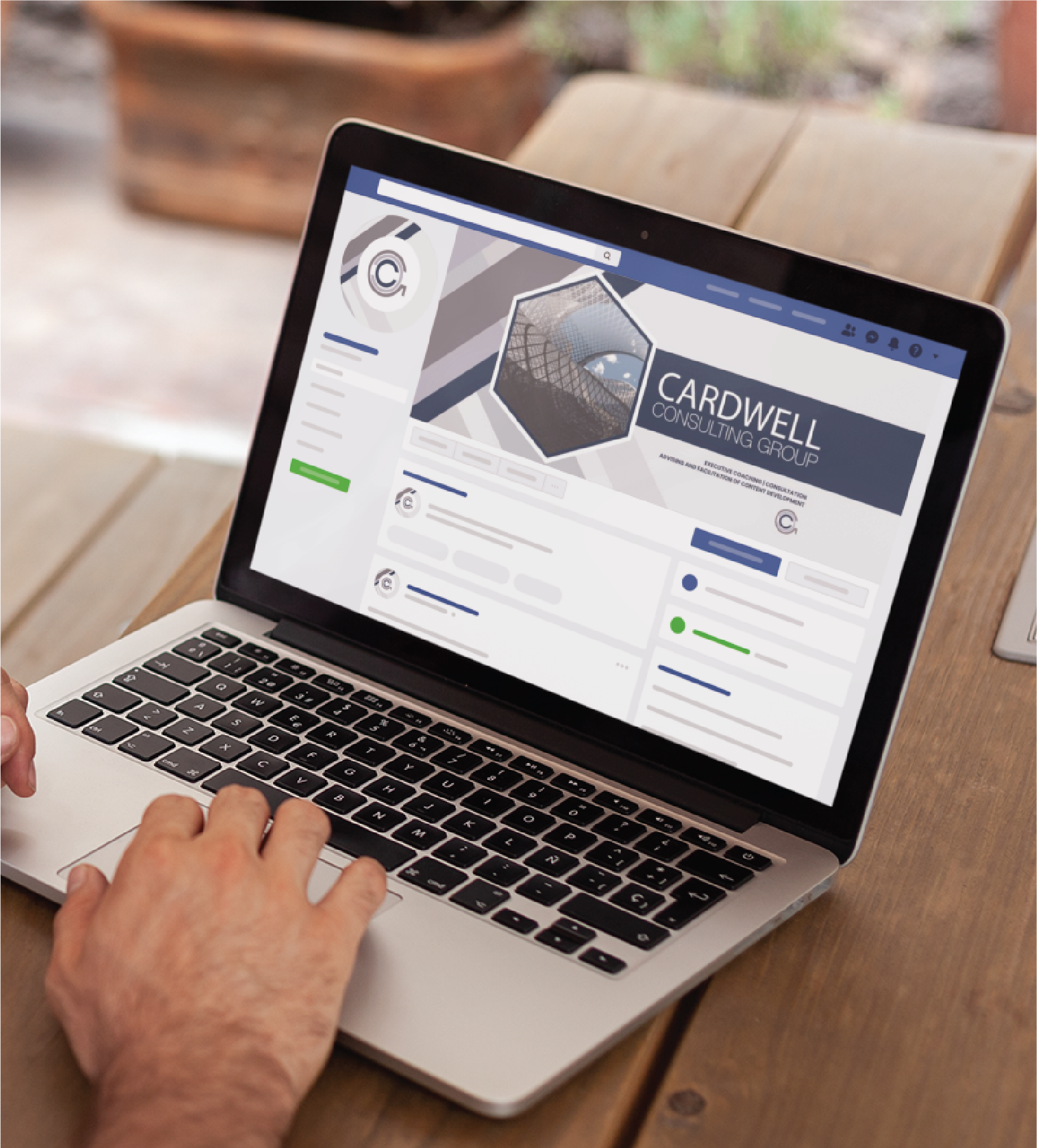 A person in Minnesota types on a laptop displaying a Facebook business page for Cardwell Consulting Group, featuring their logo, cover photo, and social media layout, while sitting at a wooden table reviewing HR Management content.