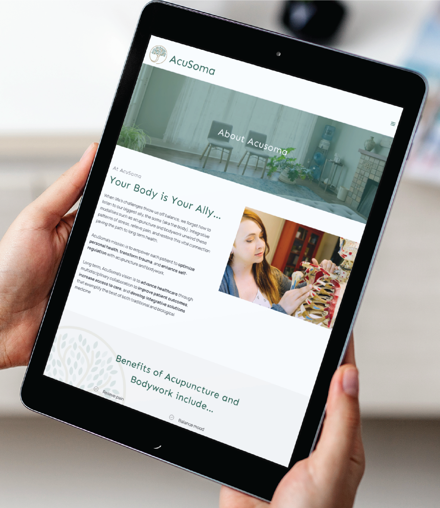A person holds a tablet displaying the AcuSoma website, showcasing professional website design focused on acupuncture and bodywork. A woman explains with a spine model, while greenery creates a serene background.