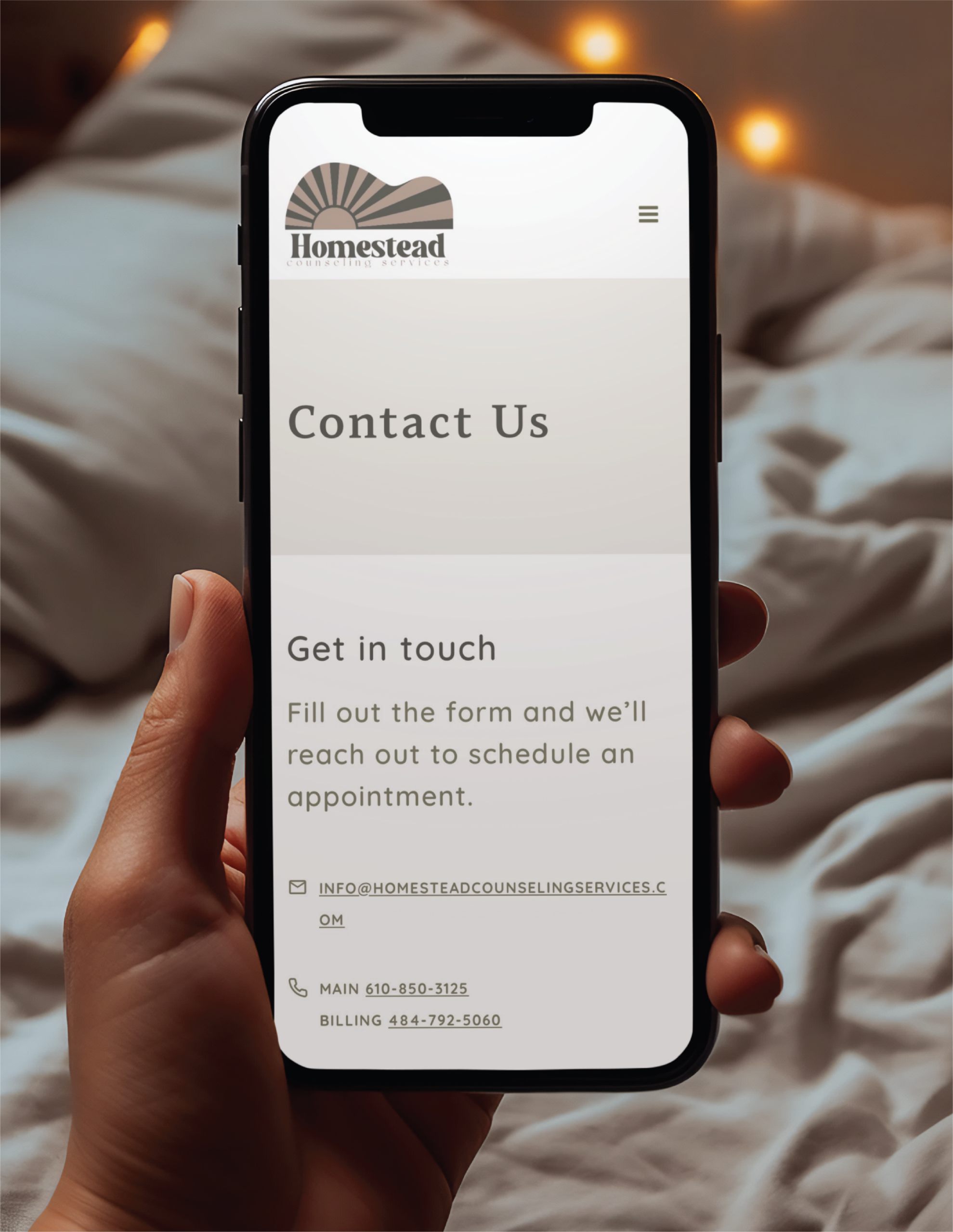A hand holds a smartphone displaying a “Contact Us” page for Homestead Counseling Services in Pennsylvania, featuring email, phone numbers, and a message about reaching out—showcasing thoughtful website design for easy appointment scheduling.