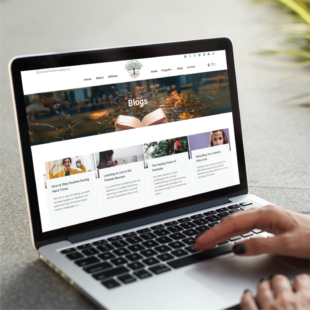 A person uses a laptop displaying a blog website featuring articles about positivity, mindfulness, and personal growth. The screen shows a header image of an open book and several blog post previews focused on website creation support services.