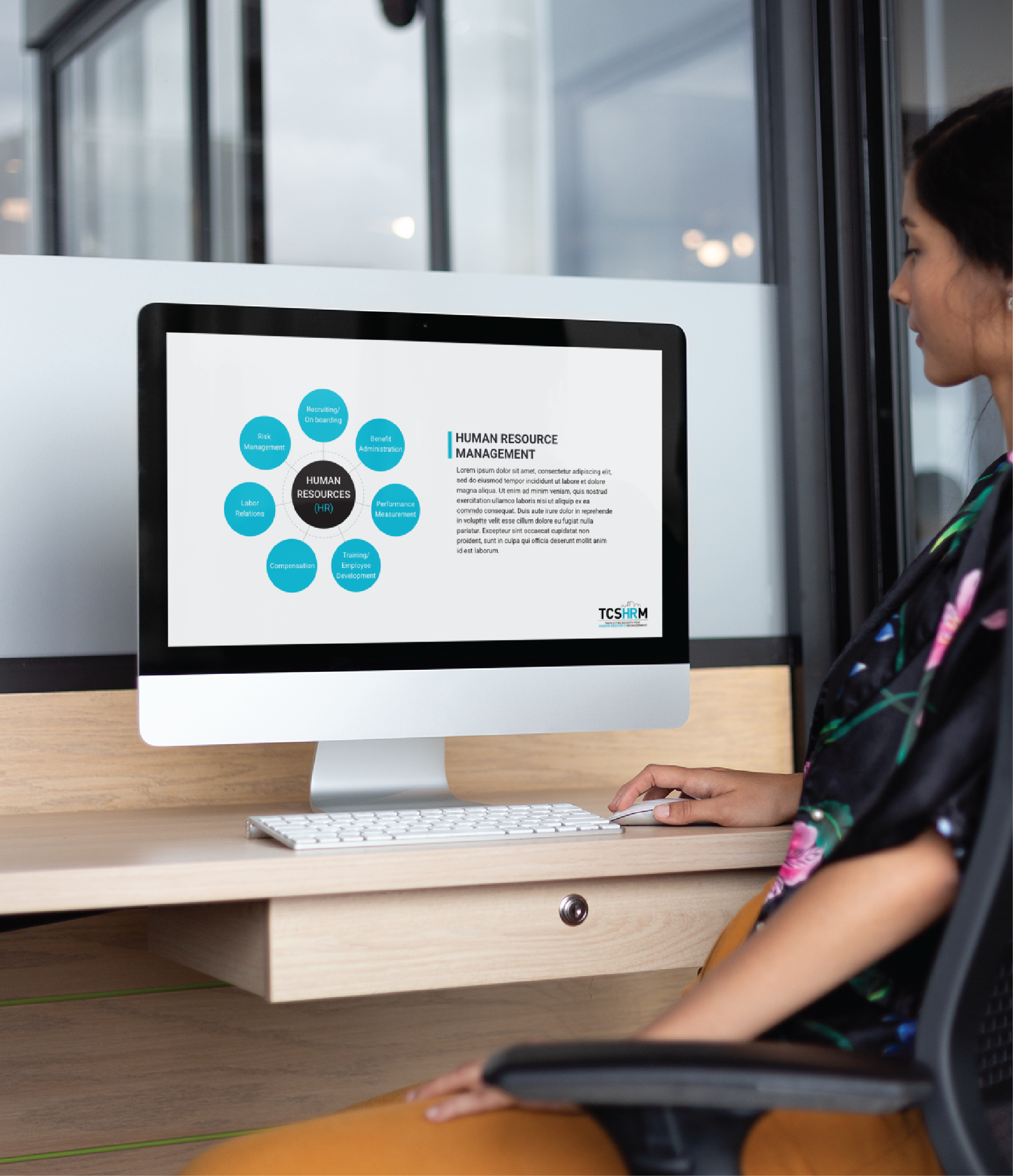 A woman sits at a desk in a Michigan office, looking at a computer screen displaying a human resource management diagram with labeled blue circles and explanatory text, perfect for creating social media graphics.