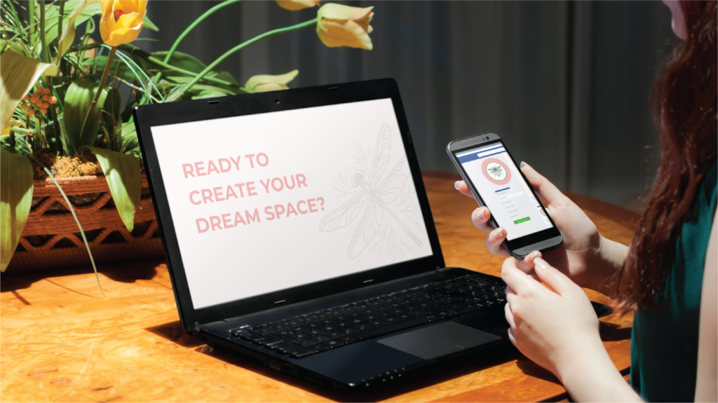 A person holds a smartphone while sitting at a table with an open laptop displaying the text Ready to create your dream space? Next to the laptop is a plant with yellow flowers—perfect inspiration for any Florida interior designer.