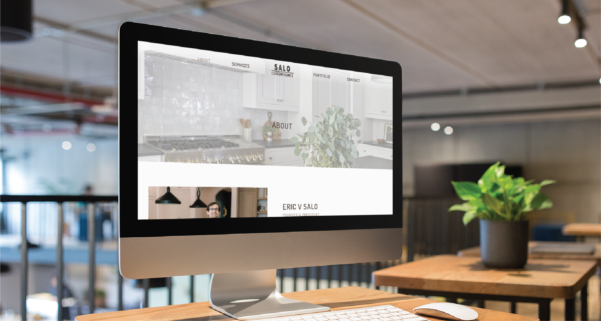 A desktop computer on a wooden desk displays a wellness practice website design in a modern, open office space. A potted plant sits by the monitor, with tables, chairs, and blurred California-inspired office decor in the background.